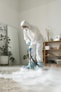 A person in protective suit cleans a carpet.