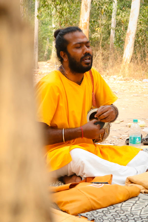 A man plays an instrument in the forest.
