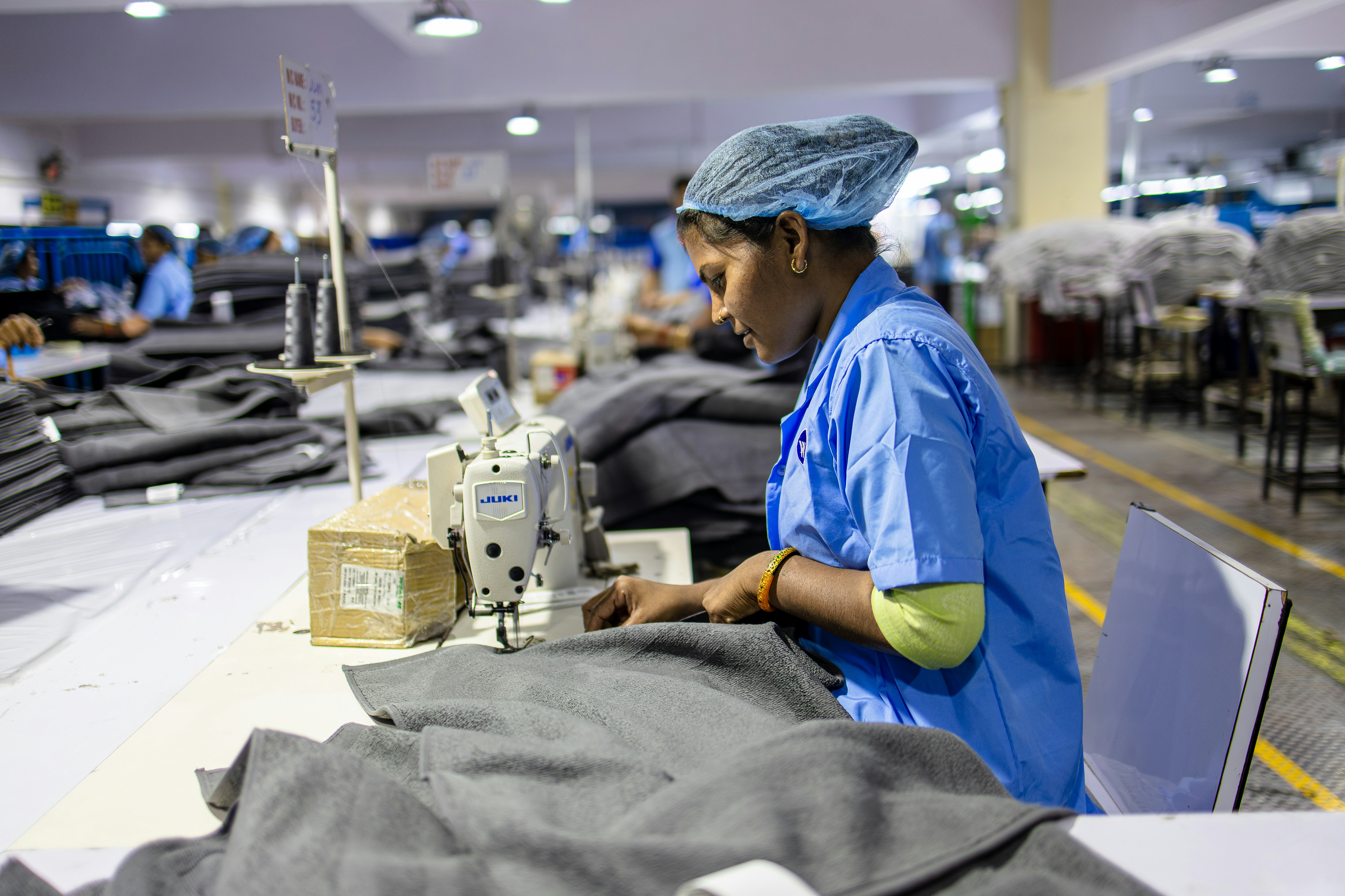 Garment worker sewing clothing at an industrial sewing station