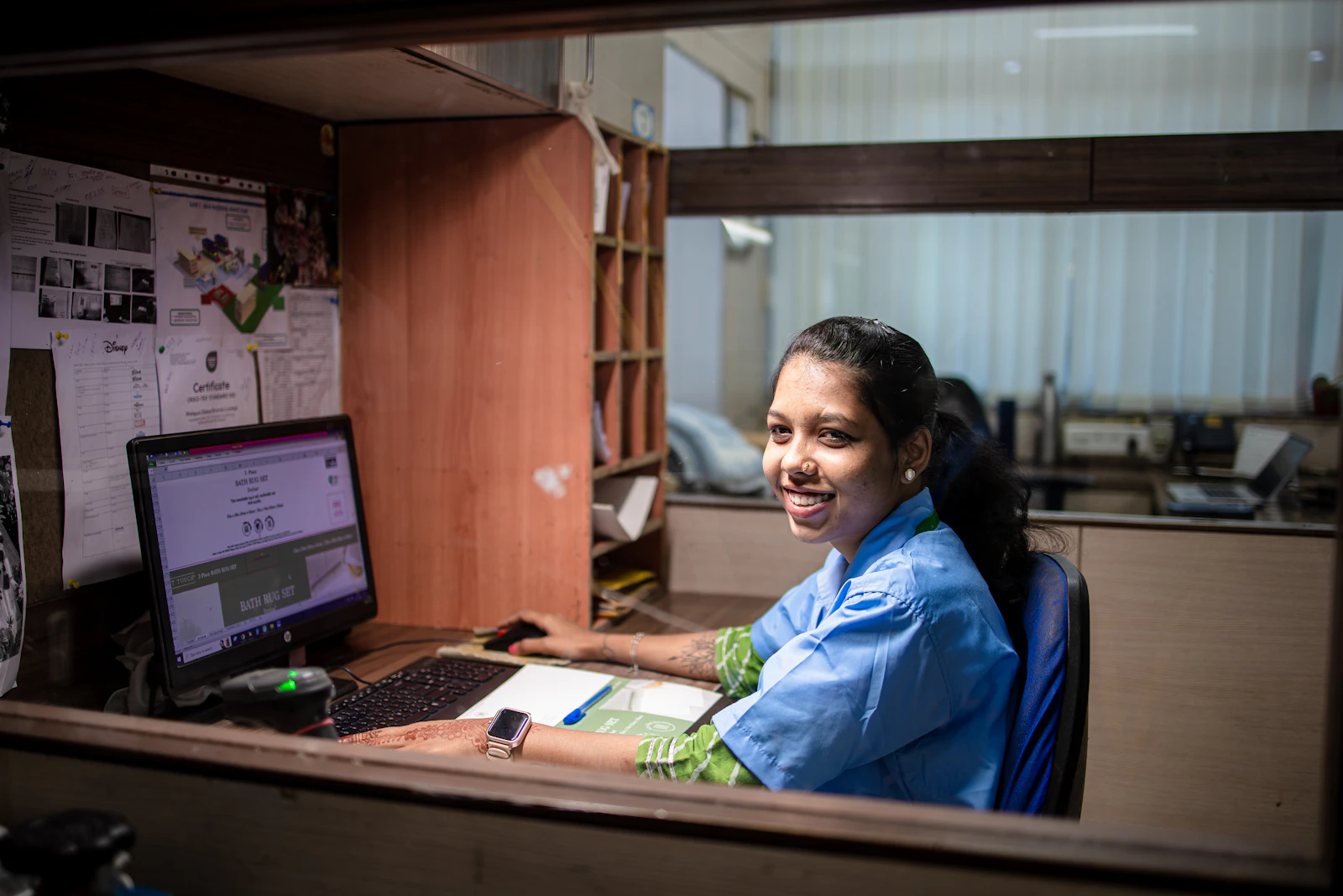 A smiling Indian professional at her office workstation