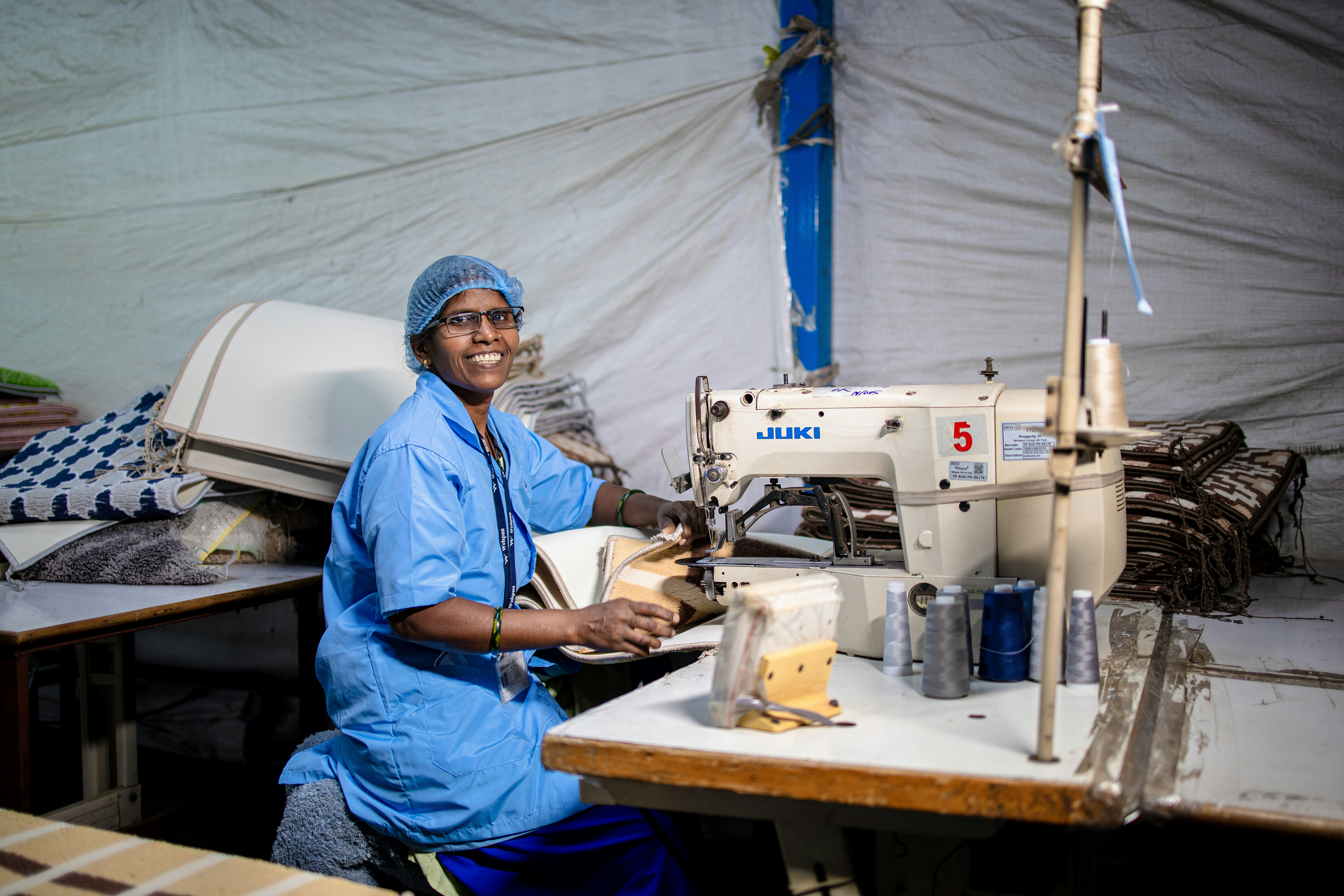 Frau näht glücklich mit einer Maschine in einer Fabrik.