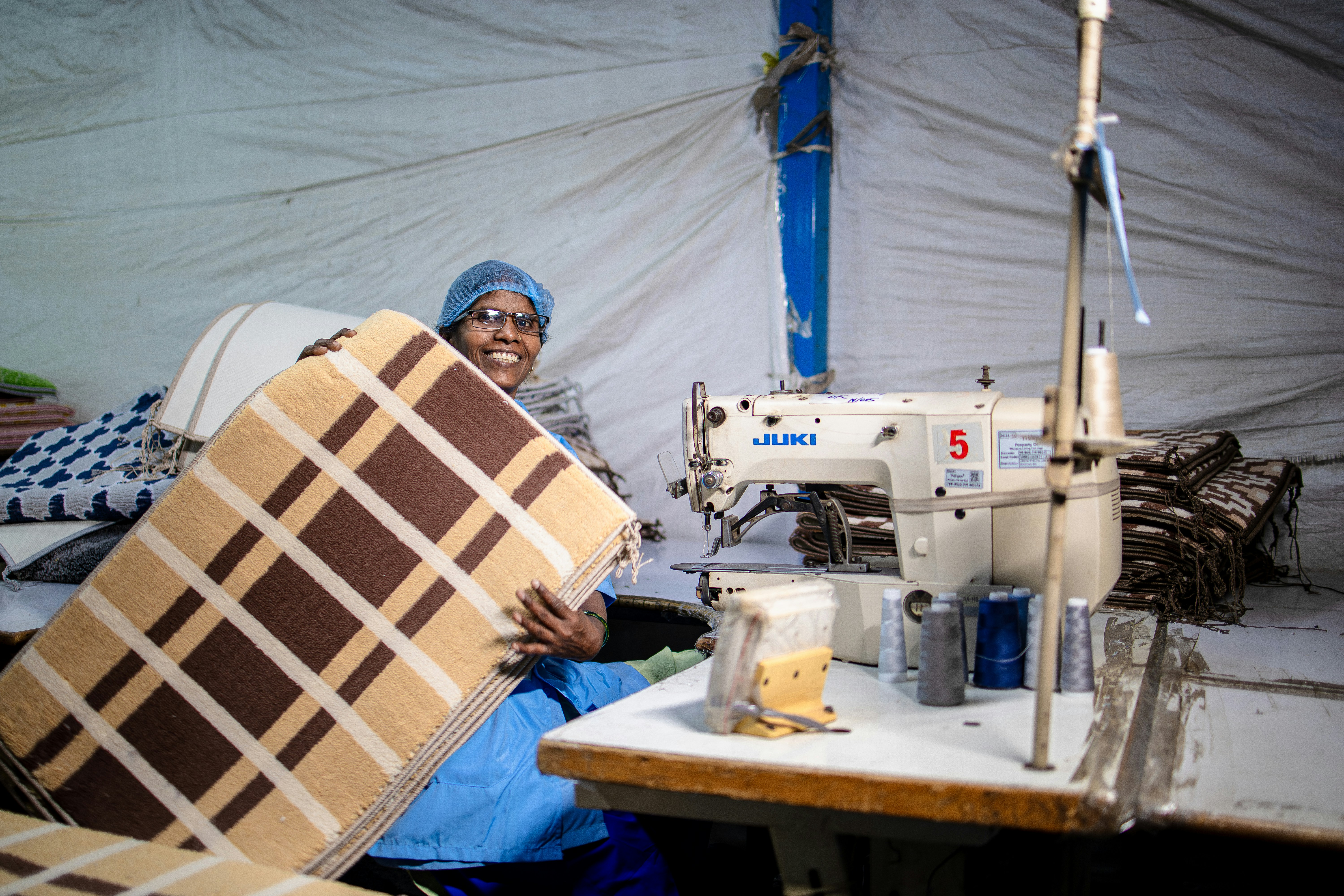 A woman sews cushions at a manufacturing facility.