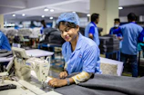 Woman uses a sewing machine in a factory.