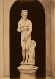 A nude statue stands within an architectural arch.