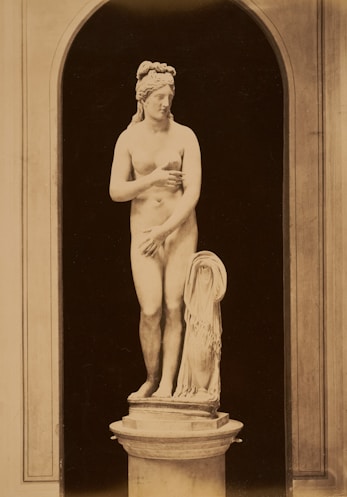 A nude statue stands within an architectural arch.