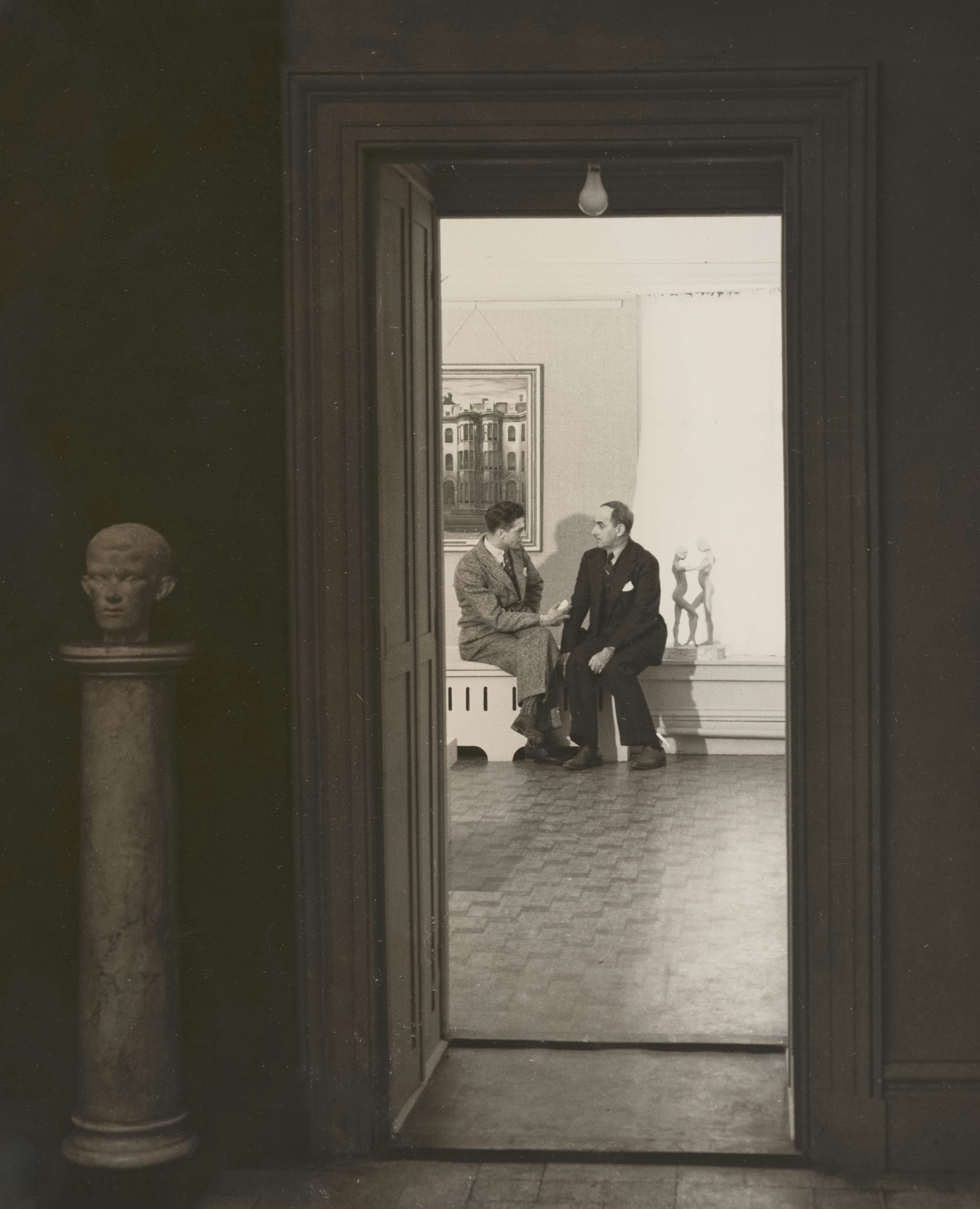 ギャラリーへの開いた戸口で会話する2人の男性。