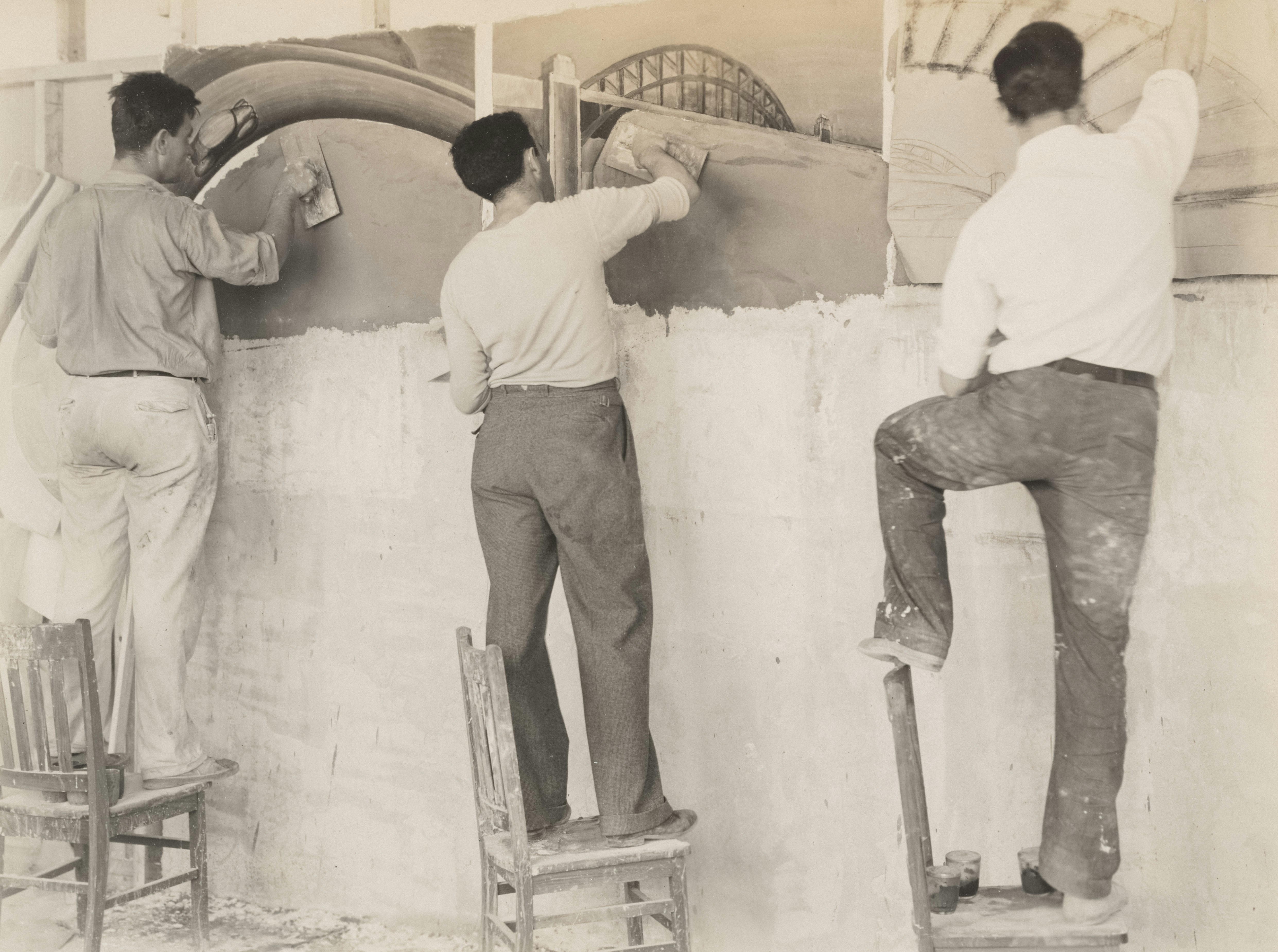 男性たちは壁に建築のイメージを漆喰で塗りつぶしています。