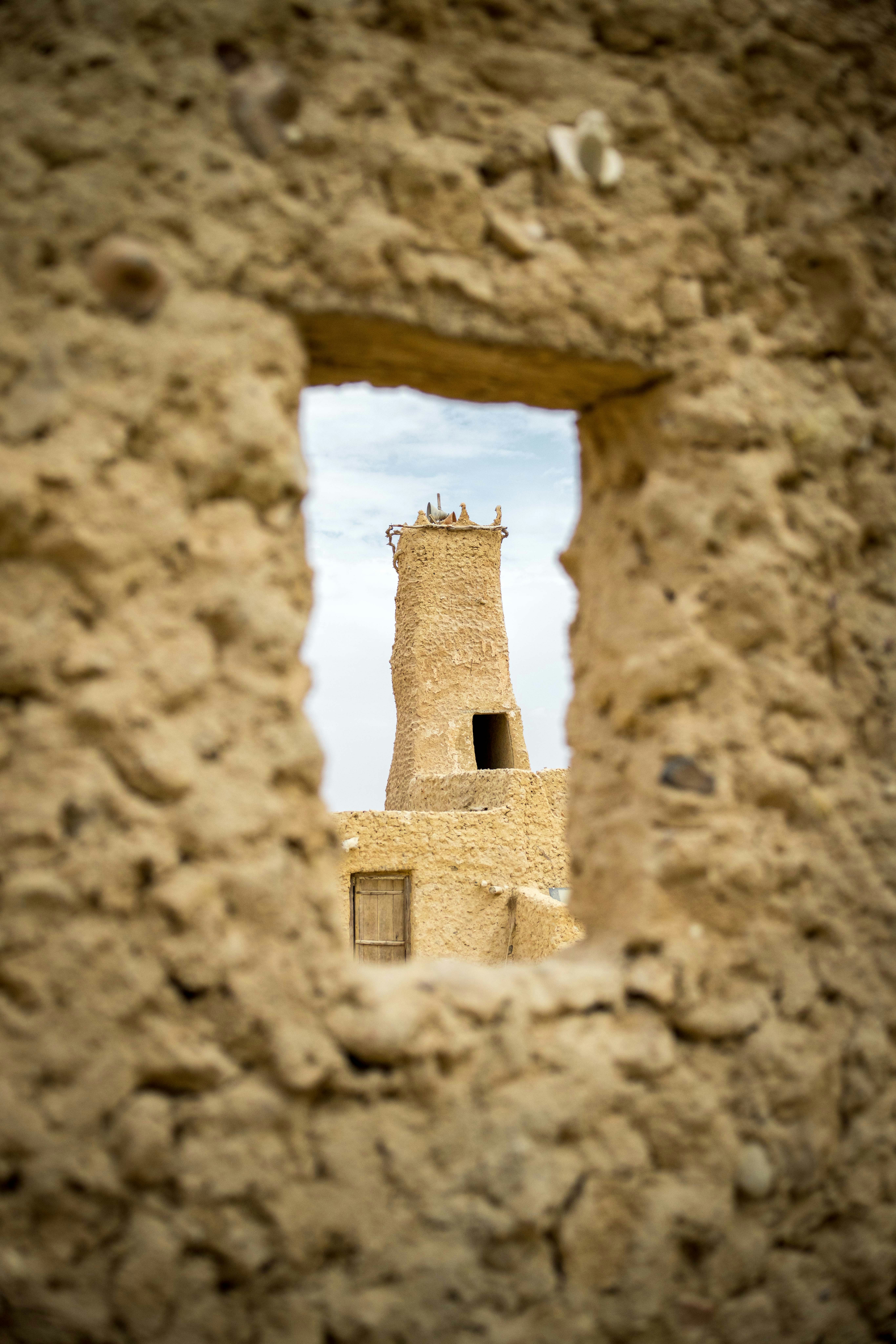 A tower peeks through a rough-hewn window.