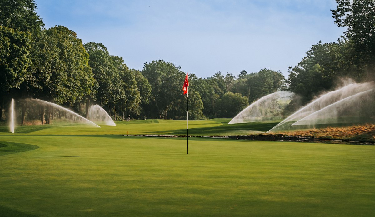 Golf course irrigation with sprinklers watering healthy turf