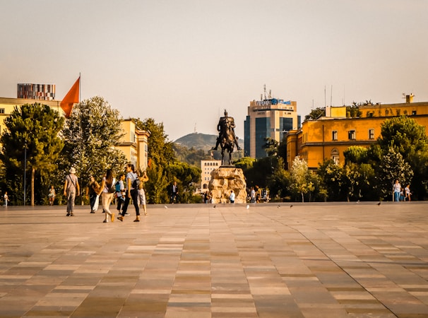 People walk in a city square with a statue.