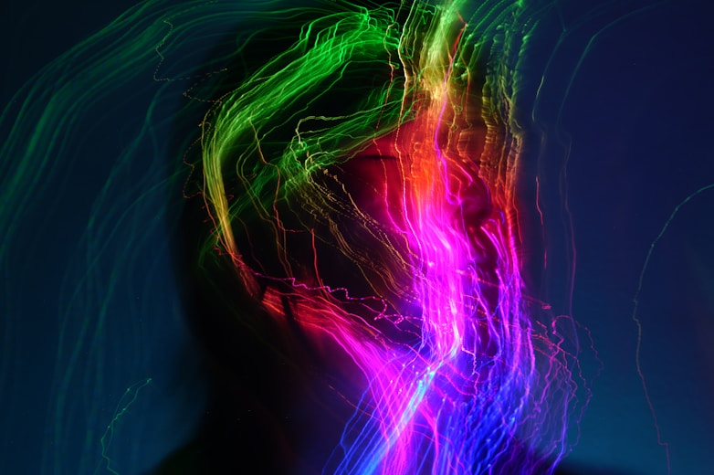 A person's face surrounded by colorful light trails.