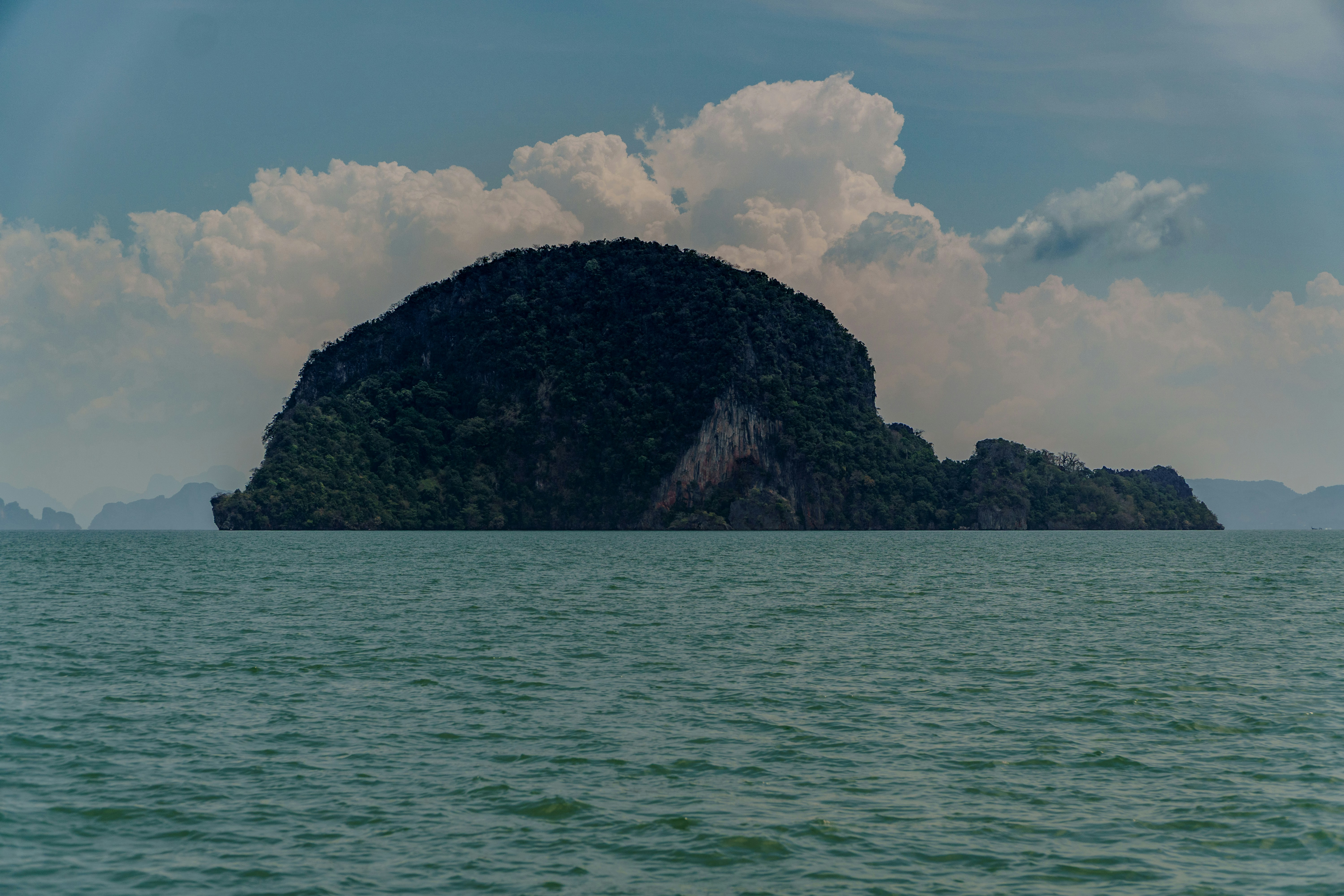 Island surrounded by water under cloudy skies.