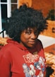 A person in a red hoodie is looking at the camera.