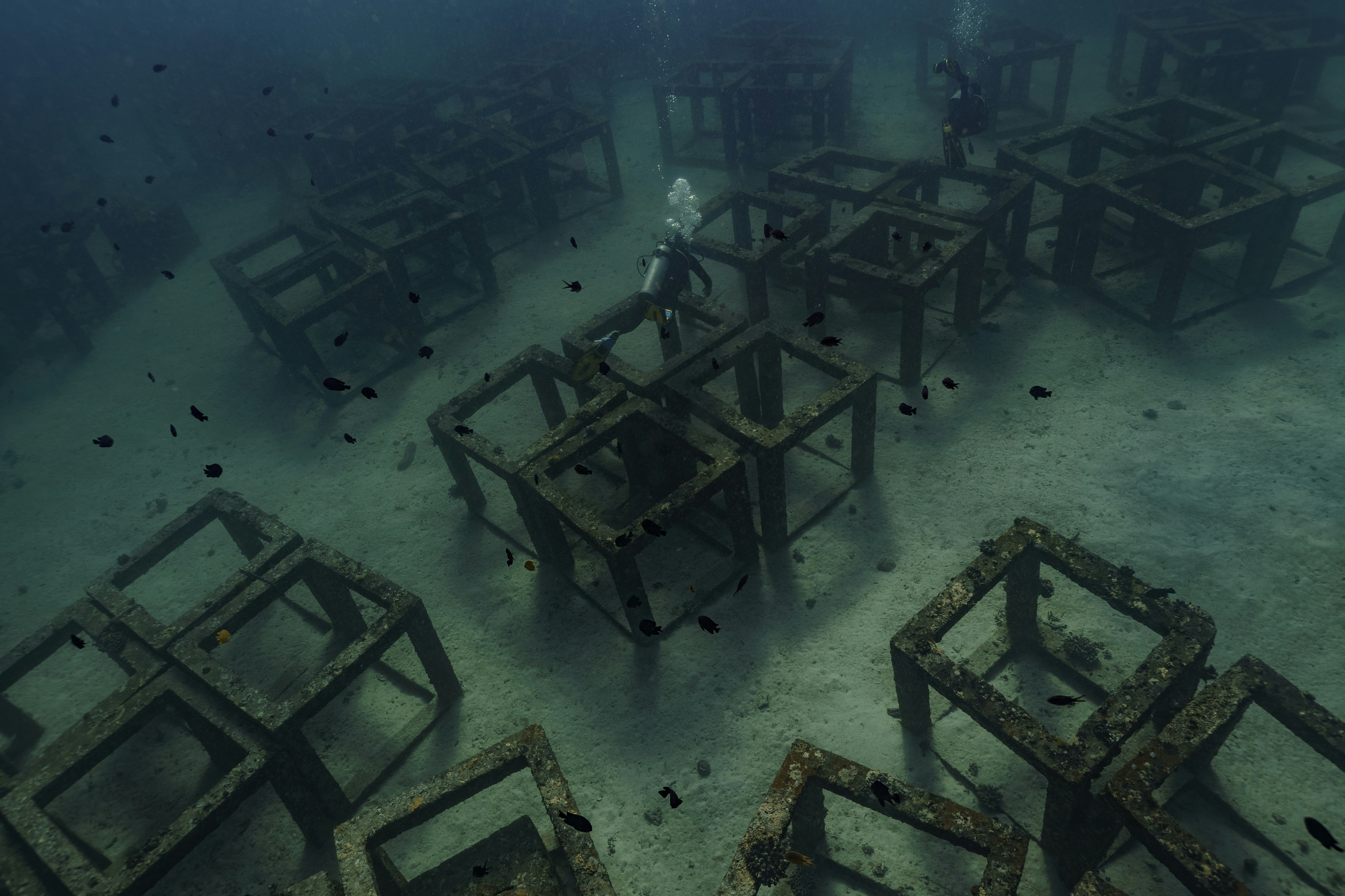 Divers explore underwater structures on the ocean floor.