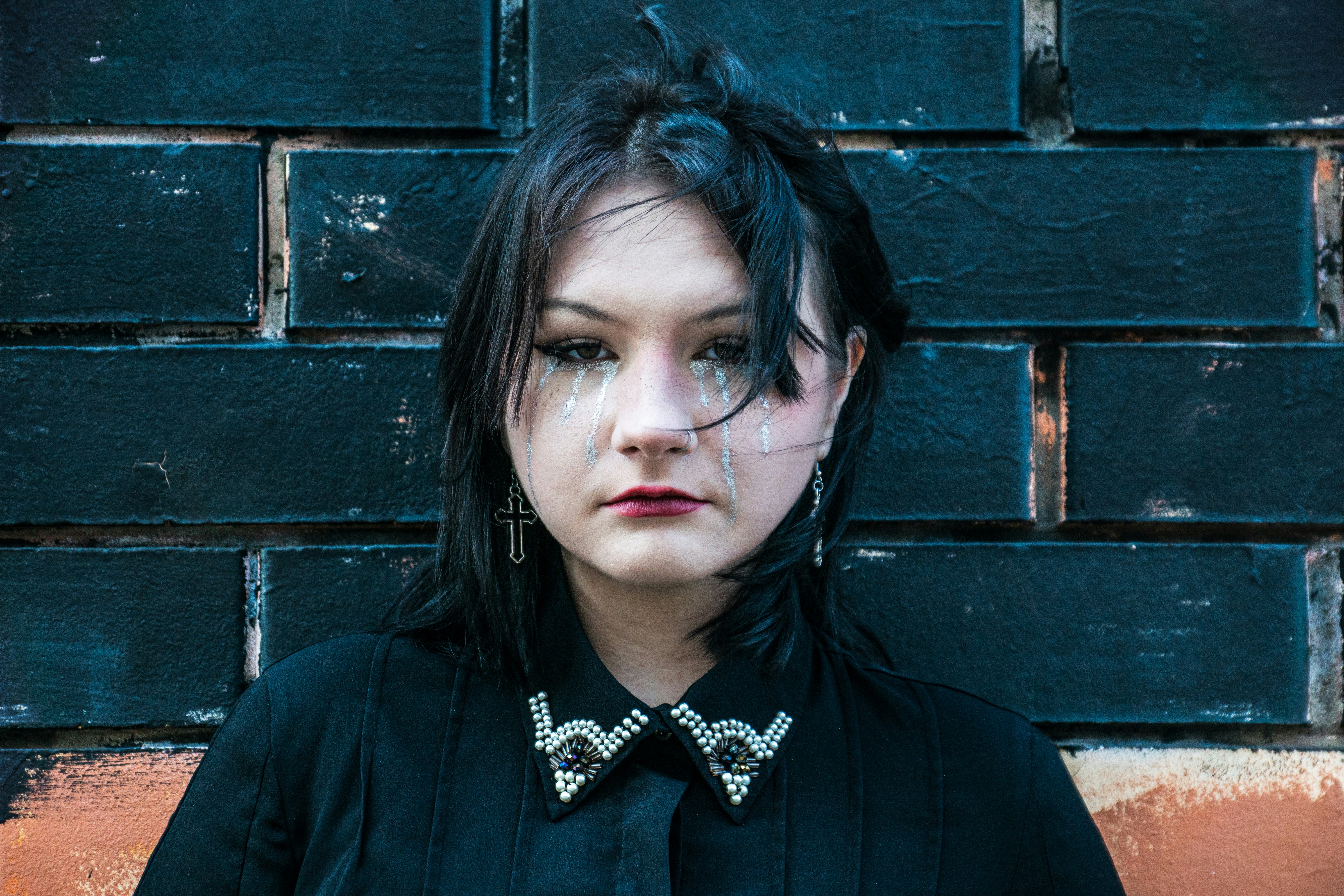 A young woman poses in front of a brick wall.