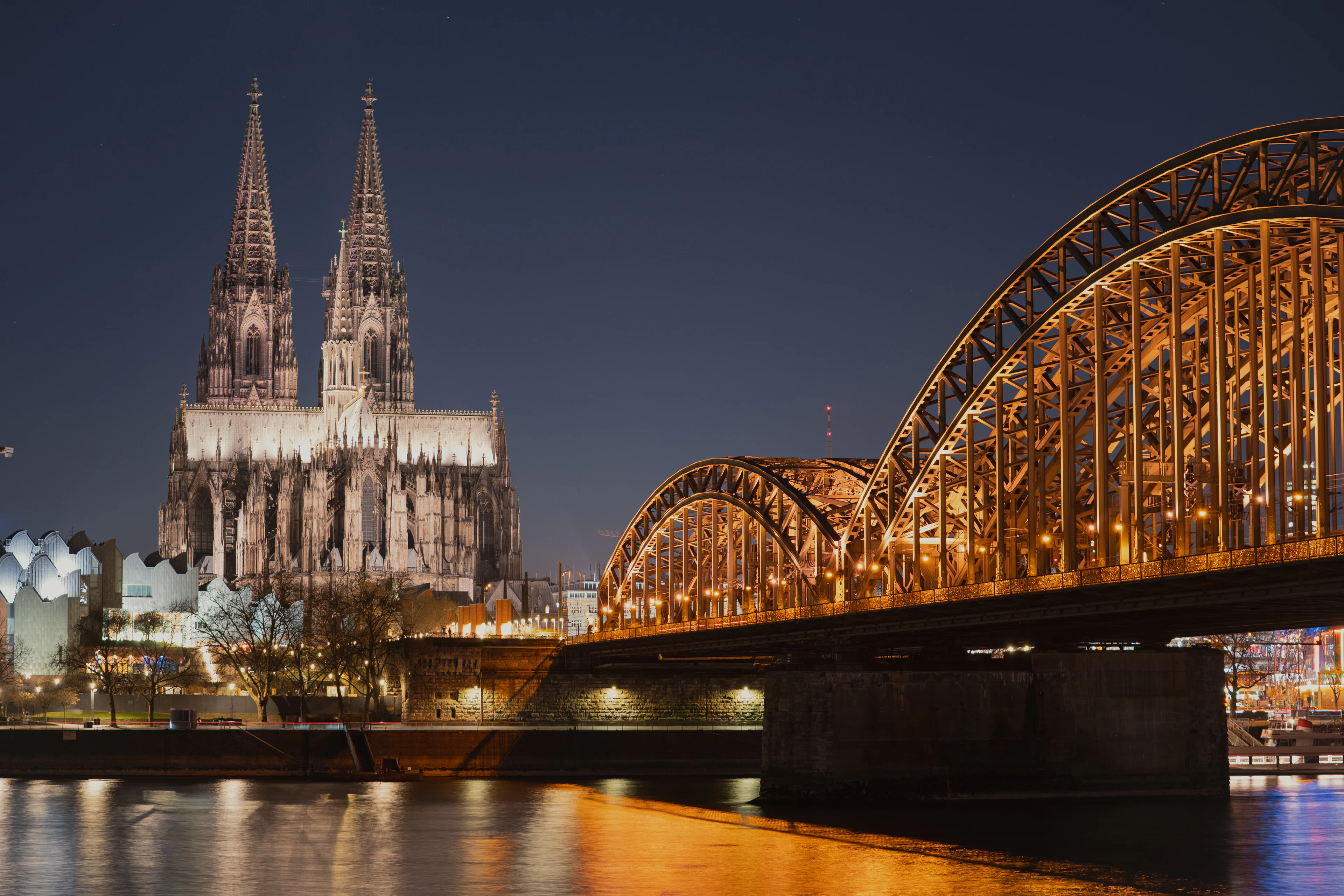 Cologne Cathedral and the Hohenzollern Bridge illuminated at night over the Rhine