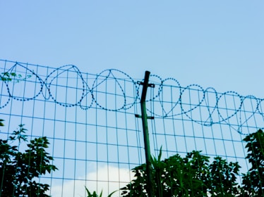 Barbed wire fence against a blue sky.