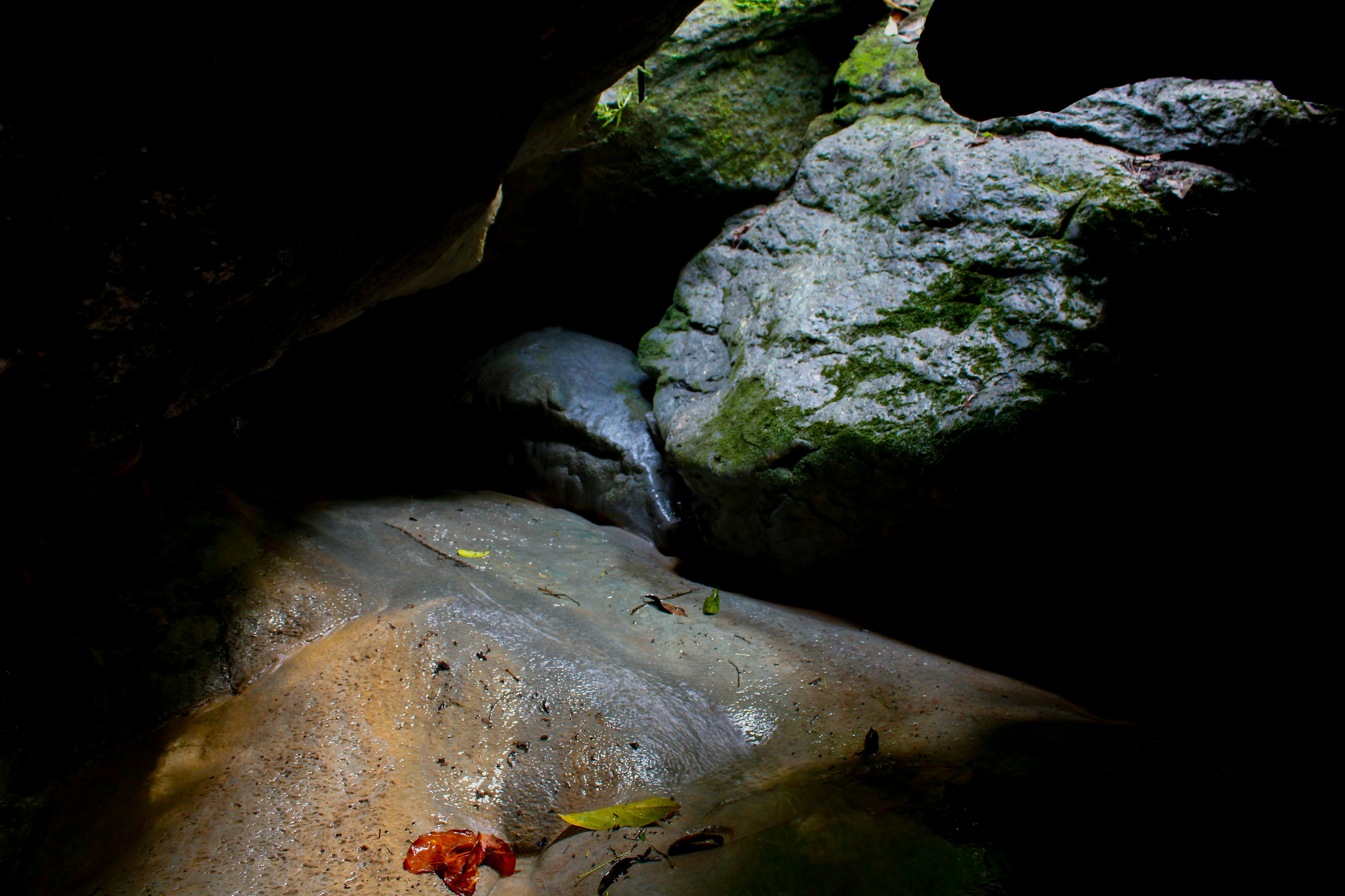 A dark cave with water flowing down rocks.