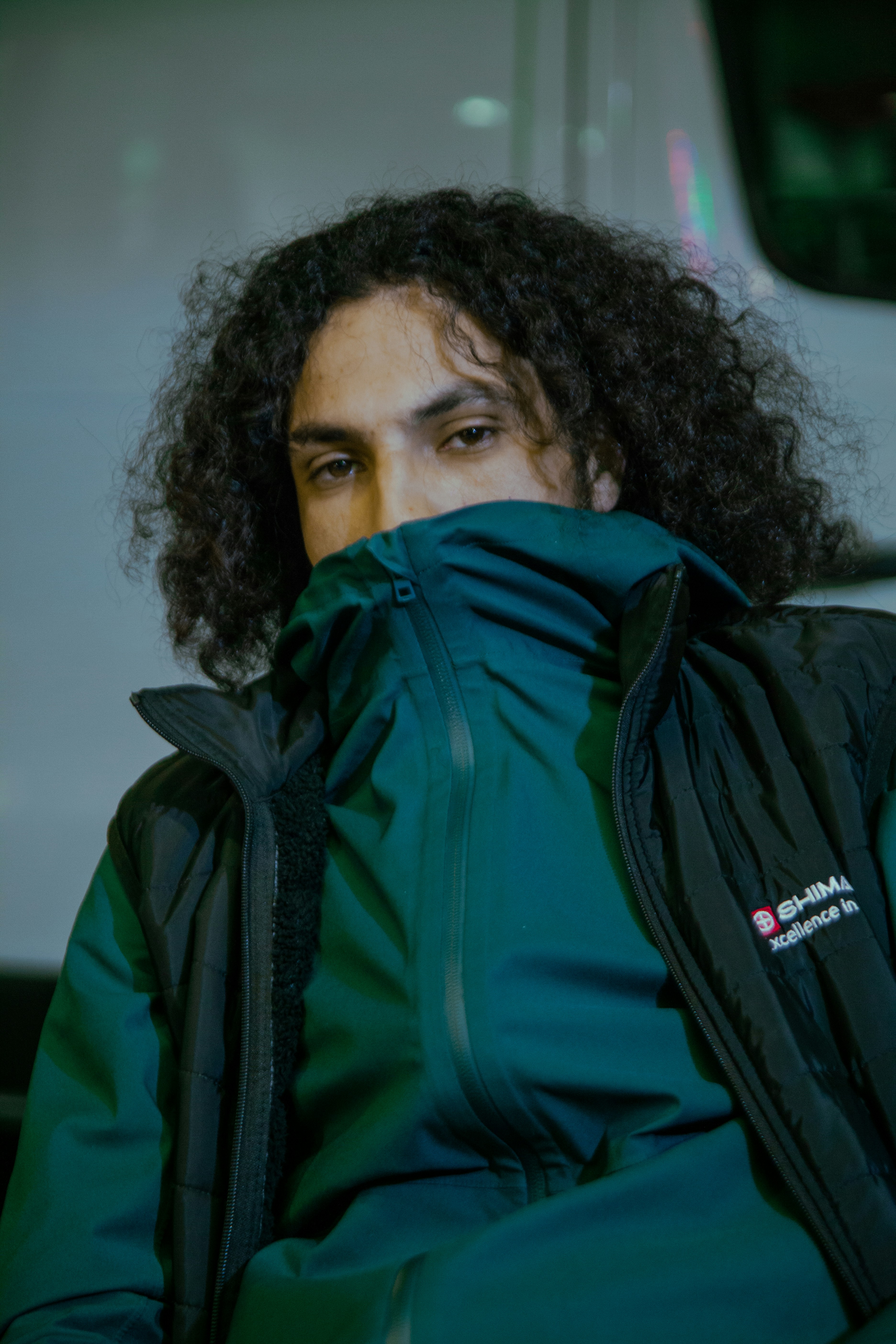 Man with curly hair, covered partially by jacket