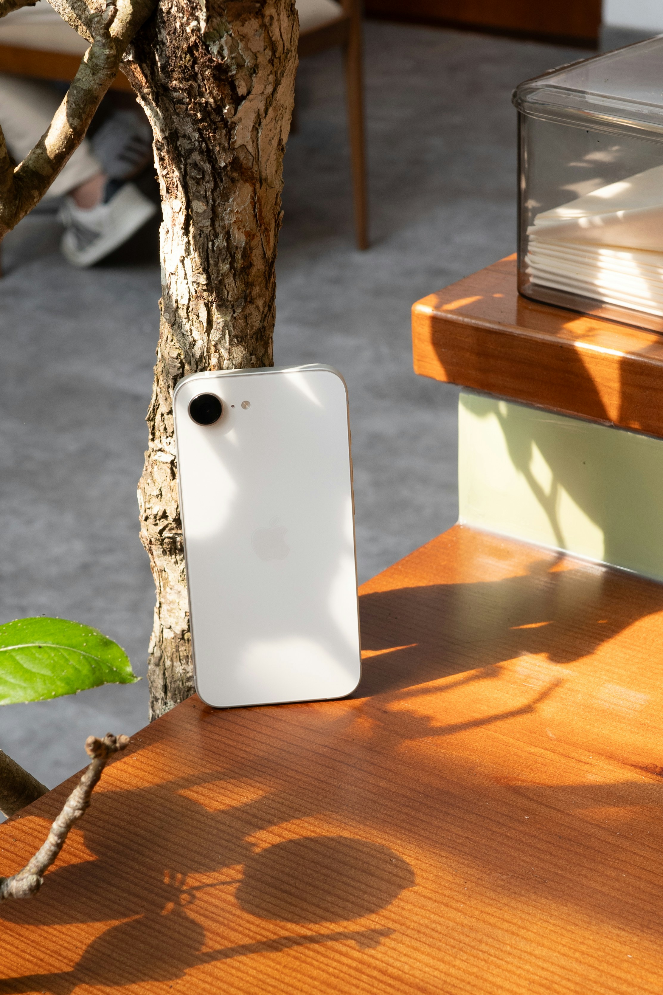 Ein weißes Handy ruht auf einem Holztisch.