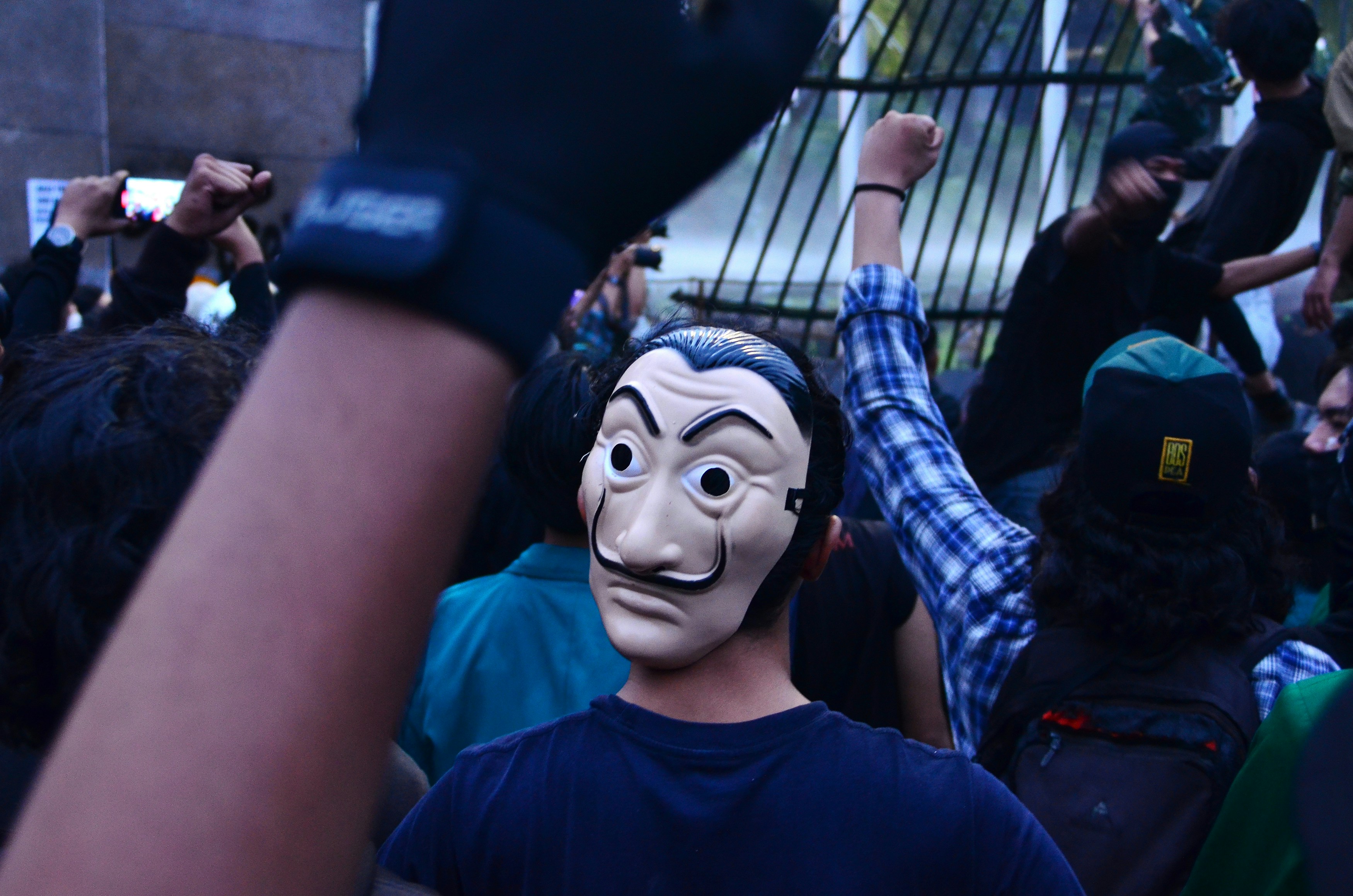 Protestors in a crowd with raised fists and mask.