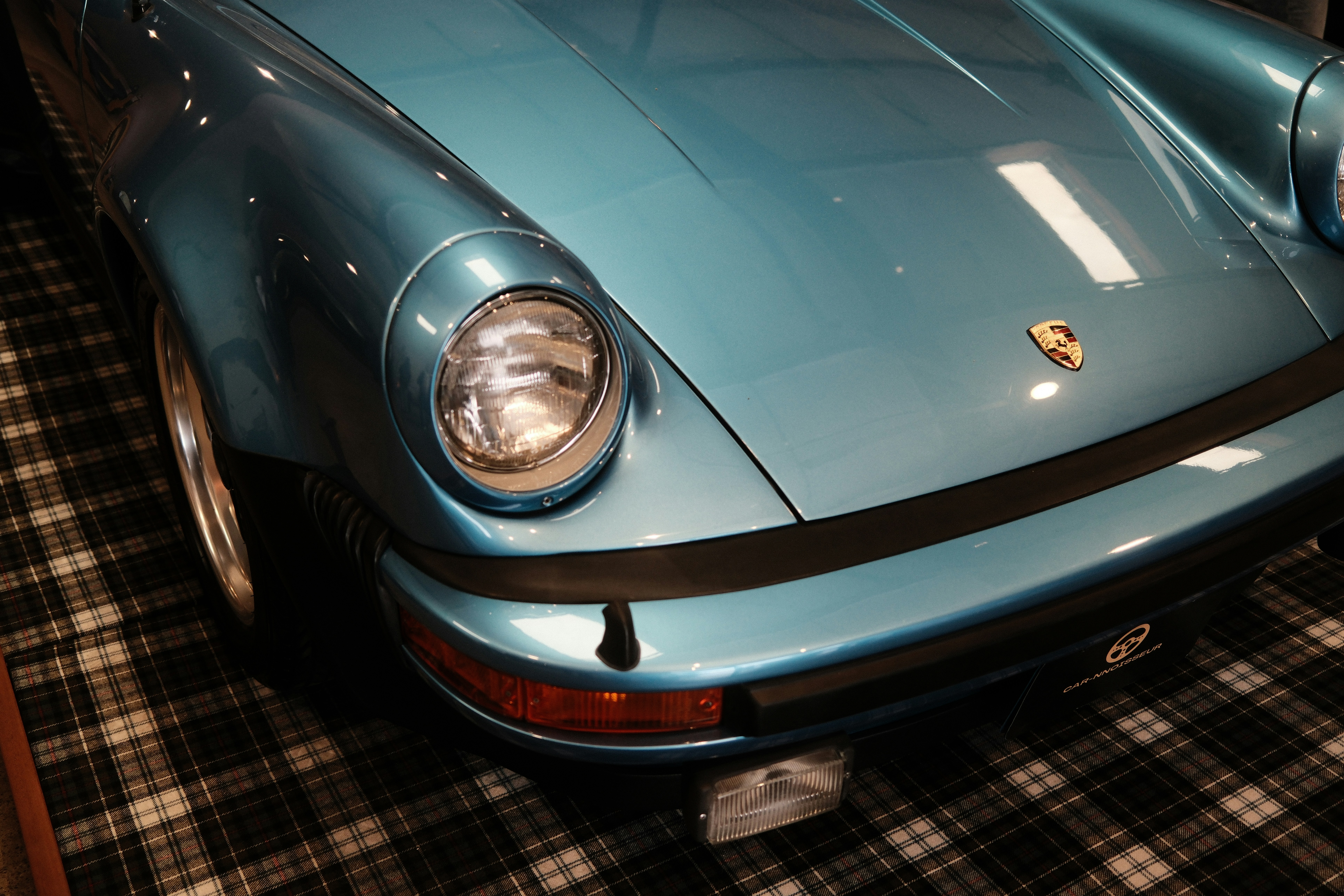 Un faro y detalle frontal de un Porsche azul.