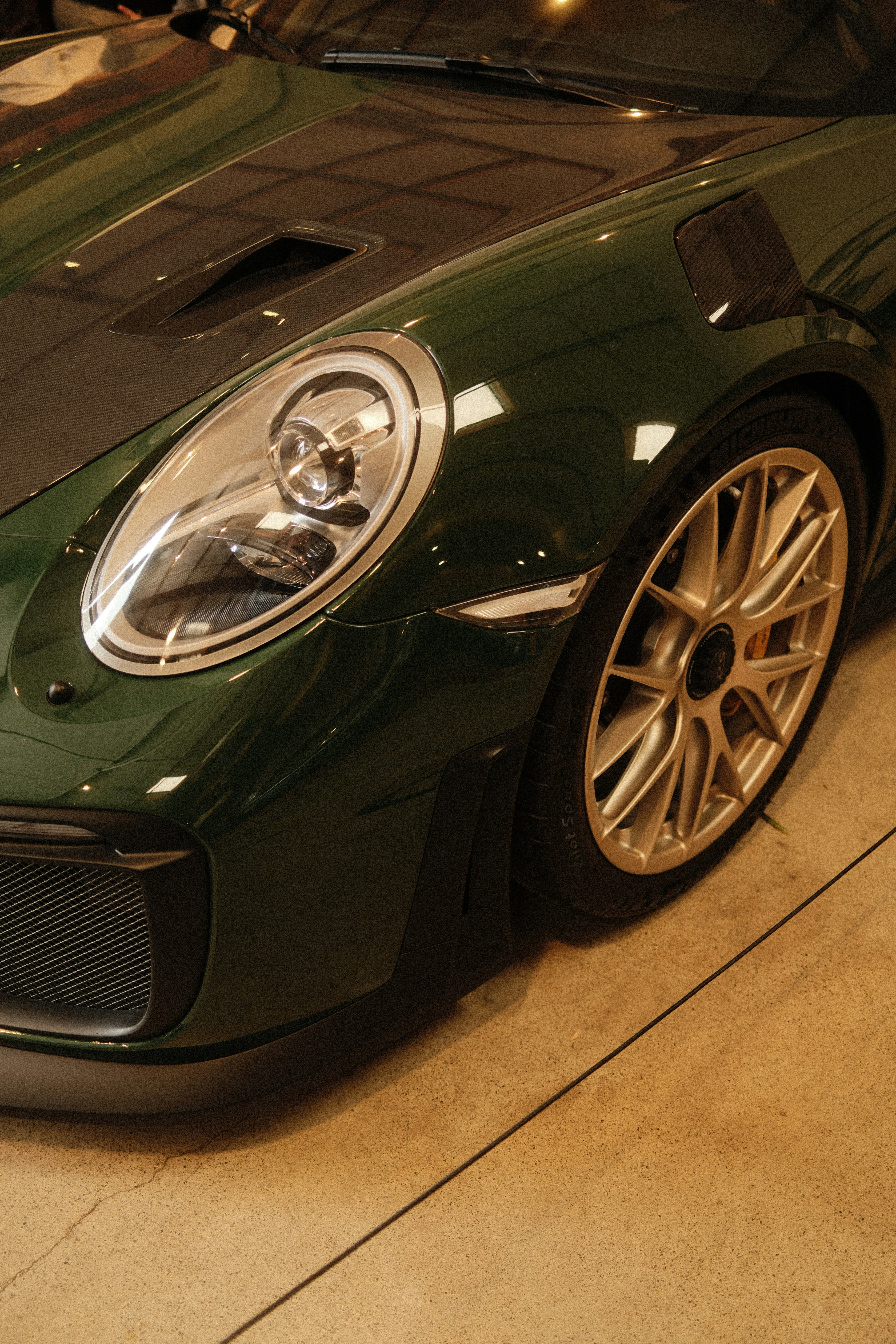 Un deportivo Porsche verde con llanta dorada.