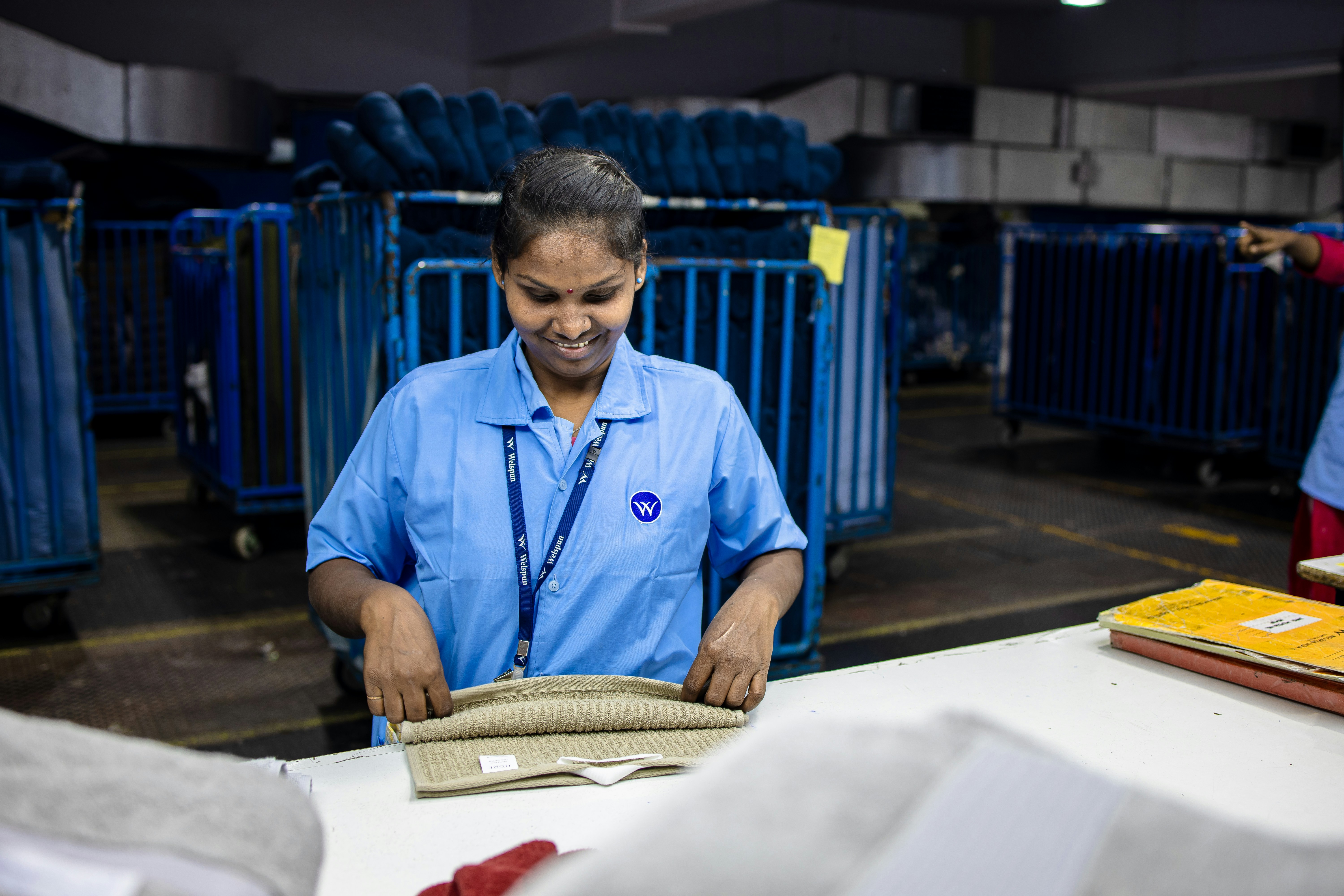 A large, modern industrial laundry facility with piles of freshly washed and folded white bed sheets and blankets for Indian Railways.