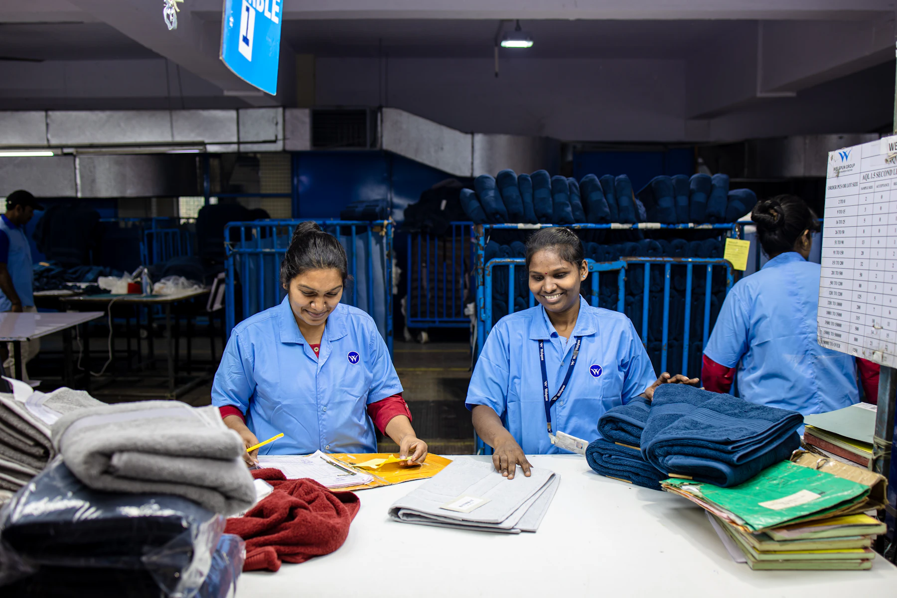 Workers sort and fold laundry in an industrial setting