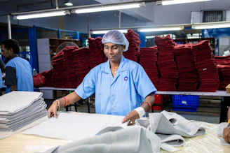 A woman folds towels in an industrial laundry.