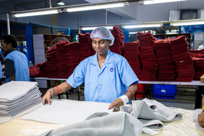 A woman folds towels in an industrial laundry.