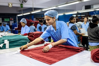 Workers assemble textiles in a factory setting.
