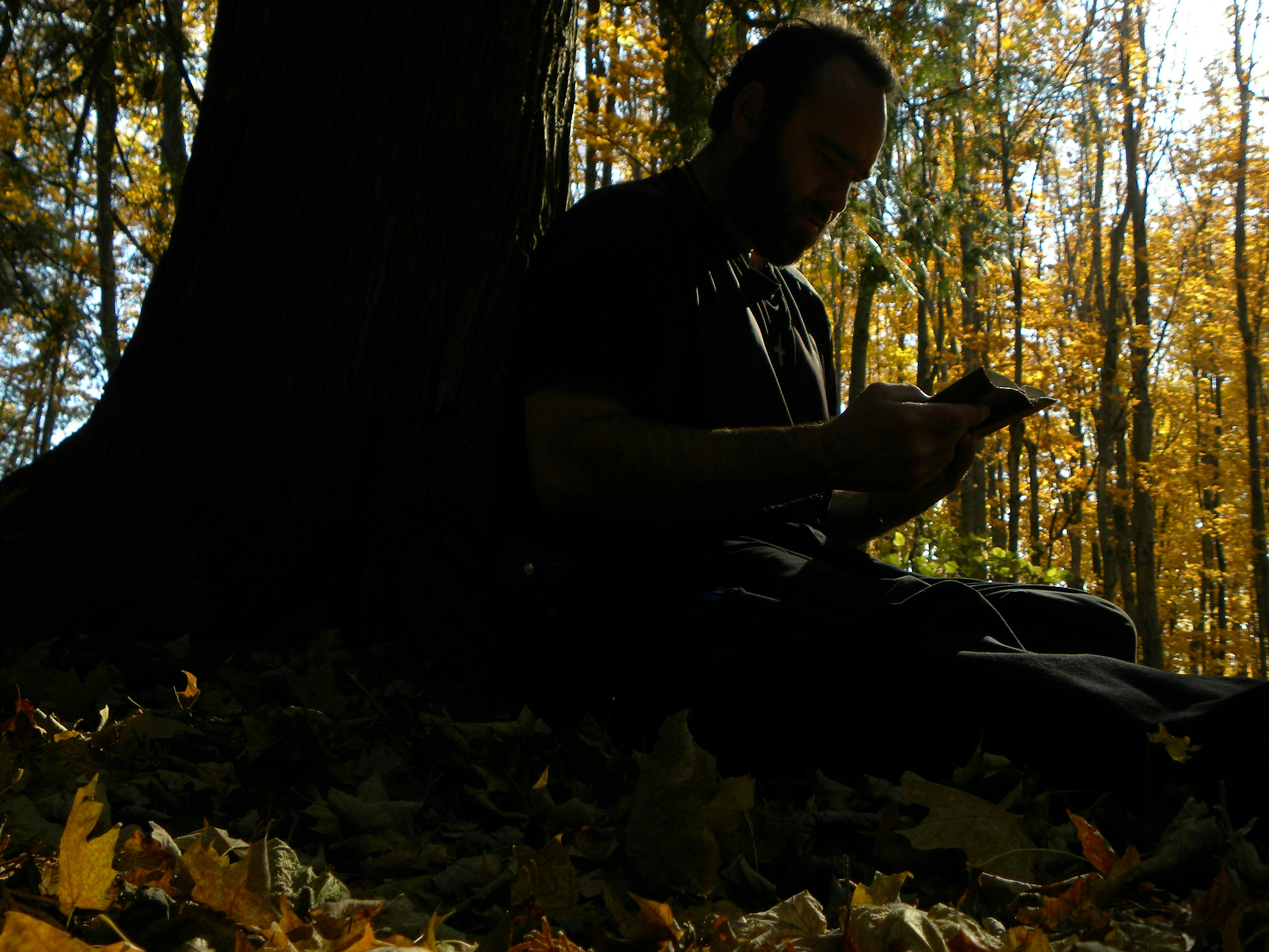 Man writes under a tree in the autumn forest.