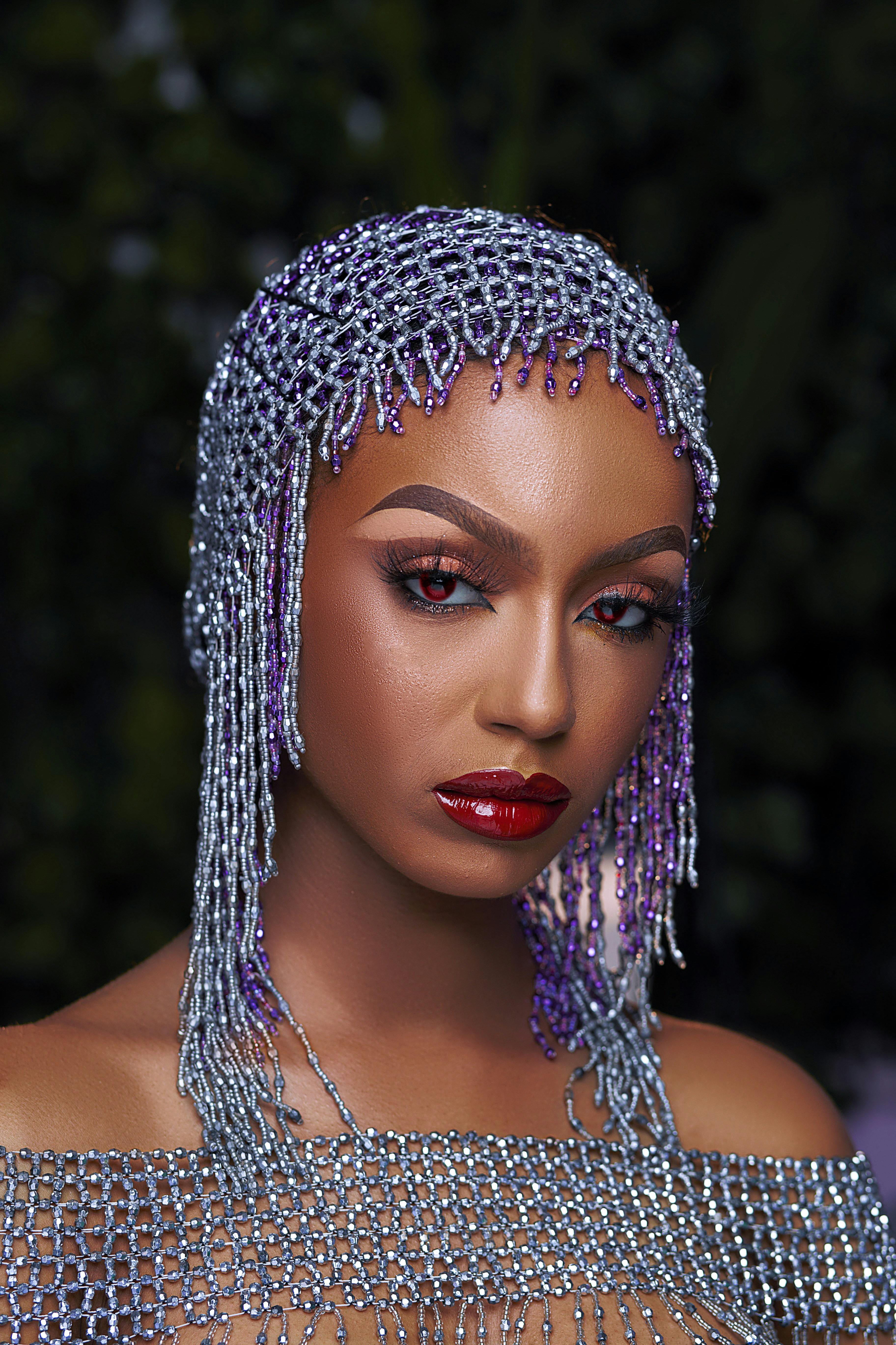 A woman models a beaded headpiece and jewelry.