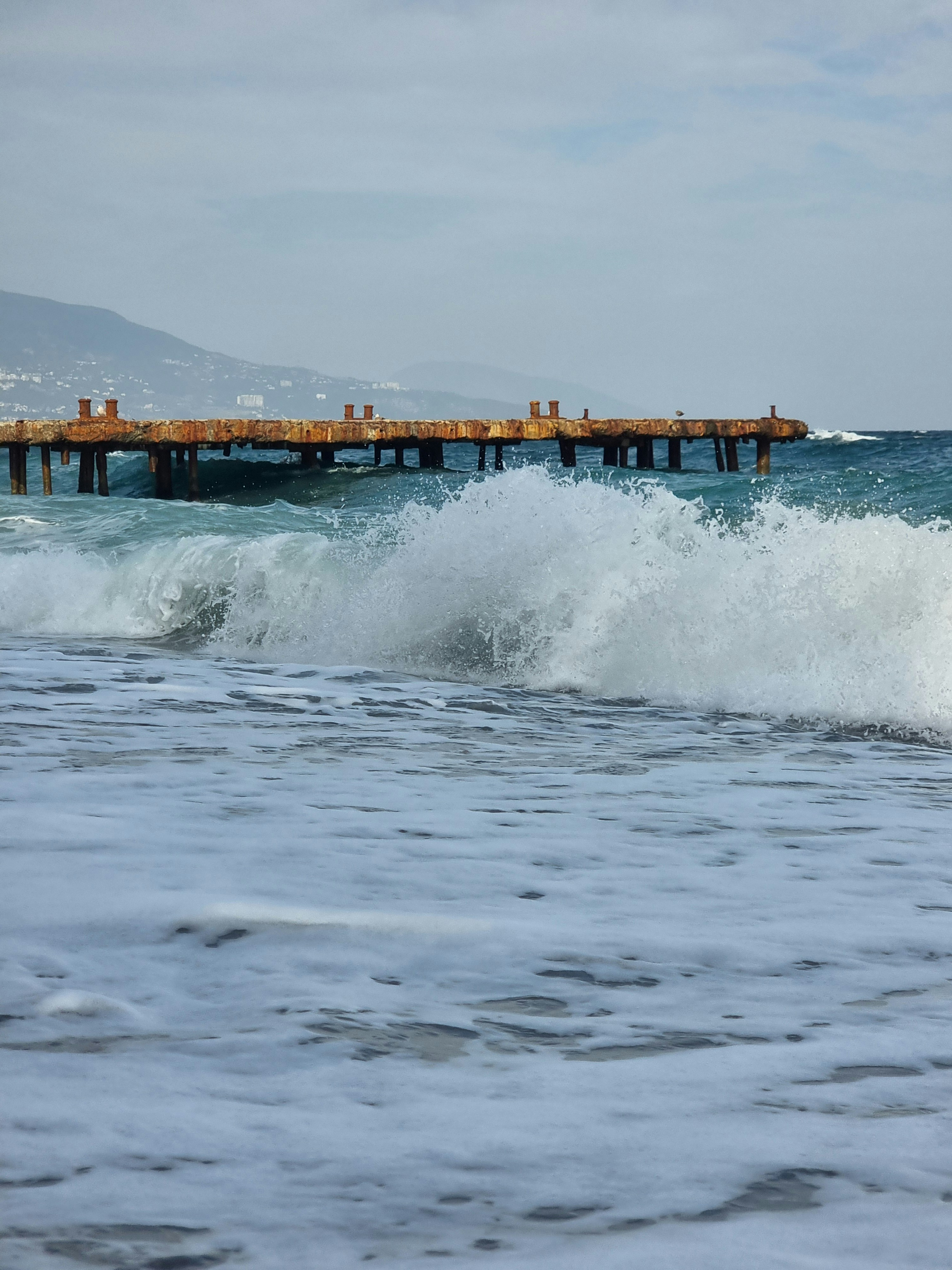 Las olas rompiendo se encuentran con un viejo muelle.