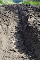 Deep tire tracks cut through muddy ground.