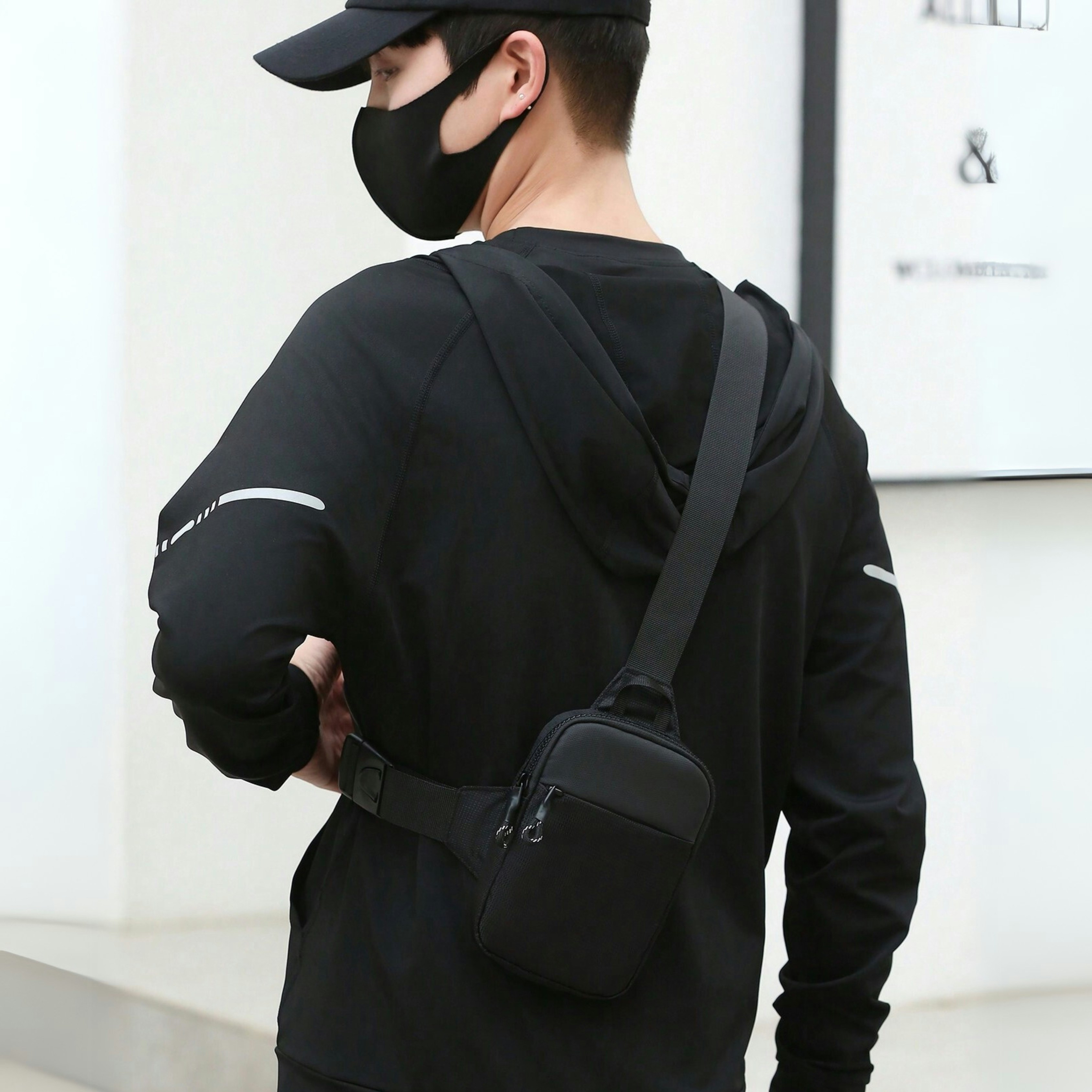 Man wearing a mask and crossbody bag.