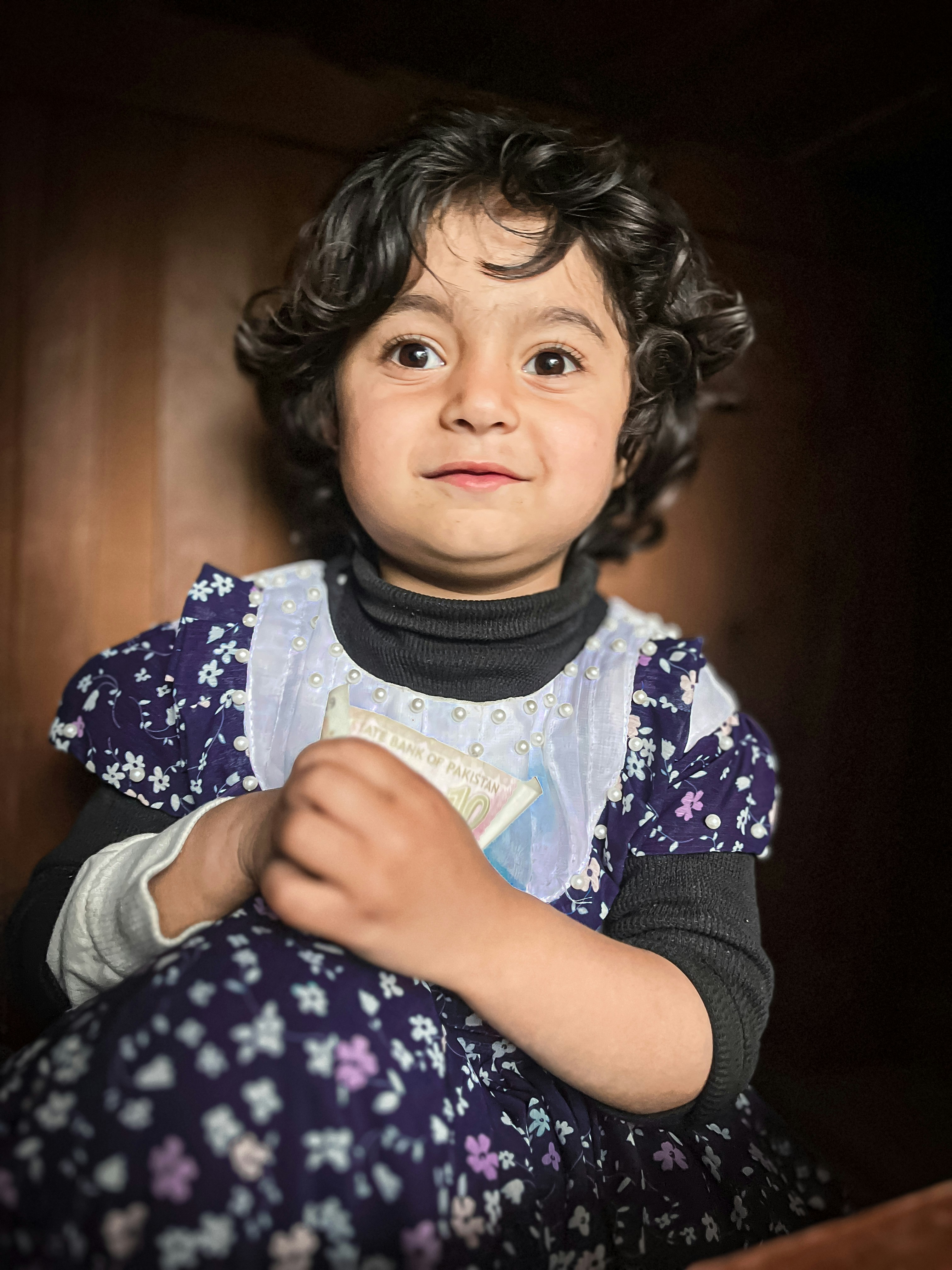 A smiling little girl in a floral dress.