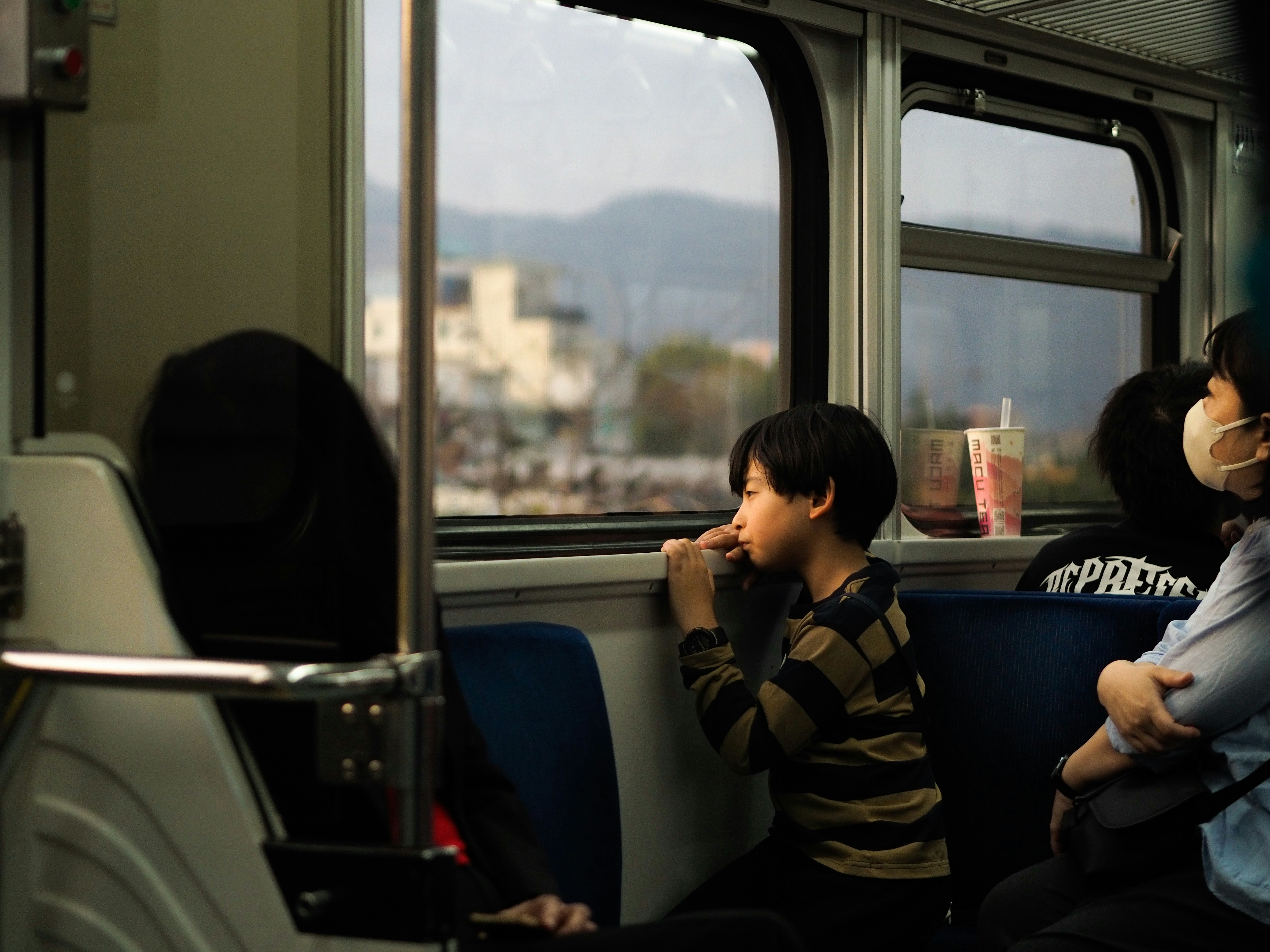Boy gazes out the train window thoughtfully.
