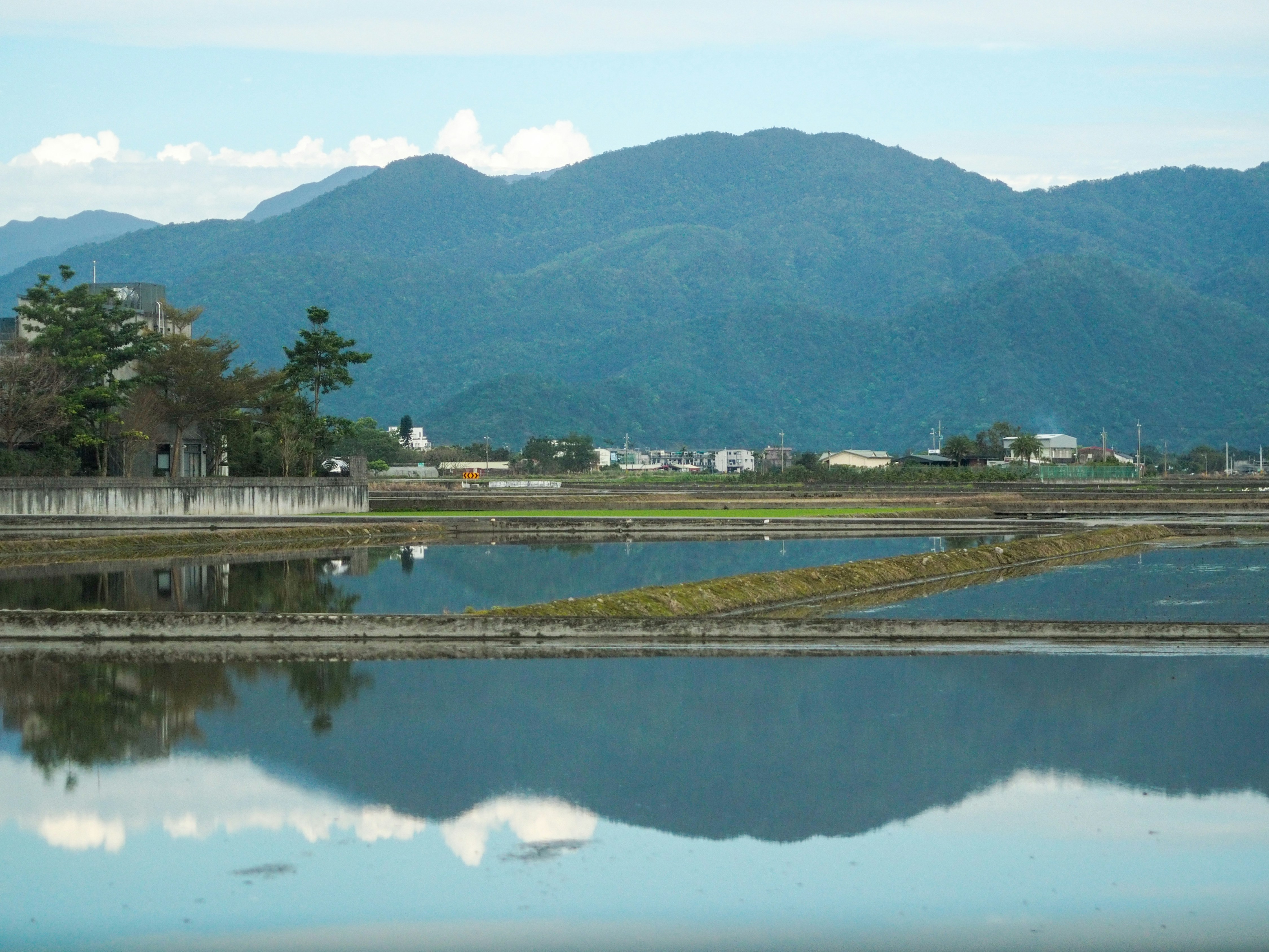 Water reflects mountains and fields in nature.