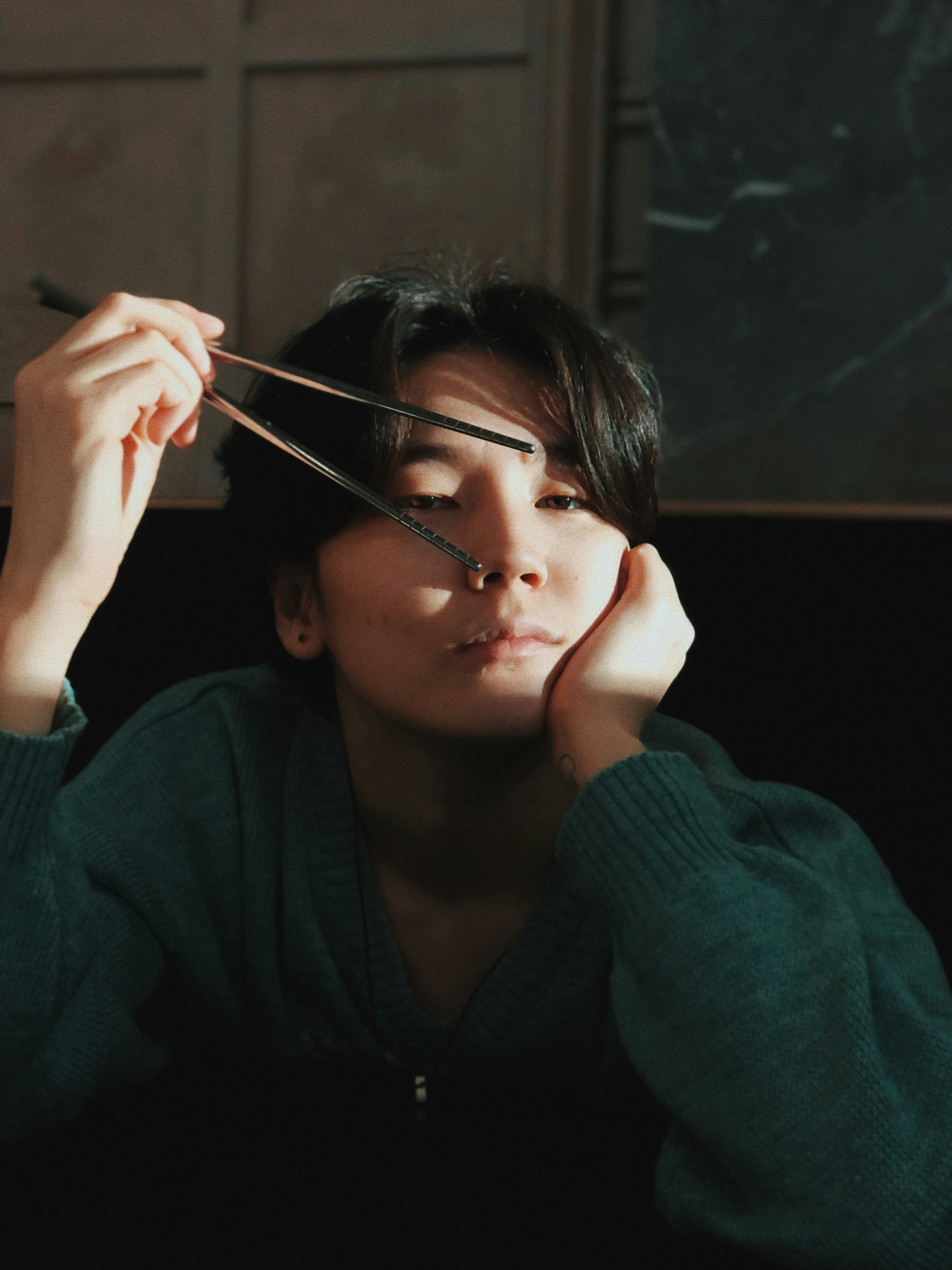 A person is holding chopsticks up to face.
