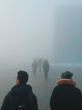 People walk through a dense, foggy atmosphere.