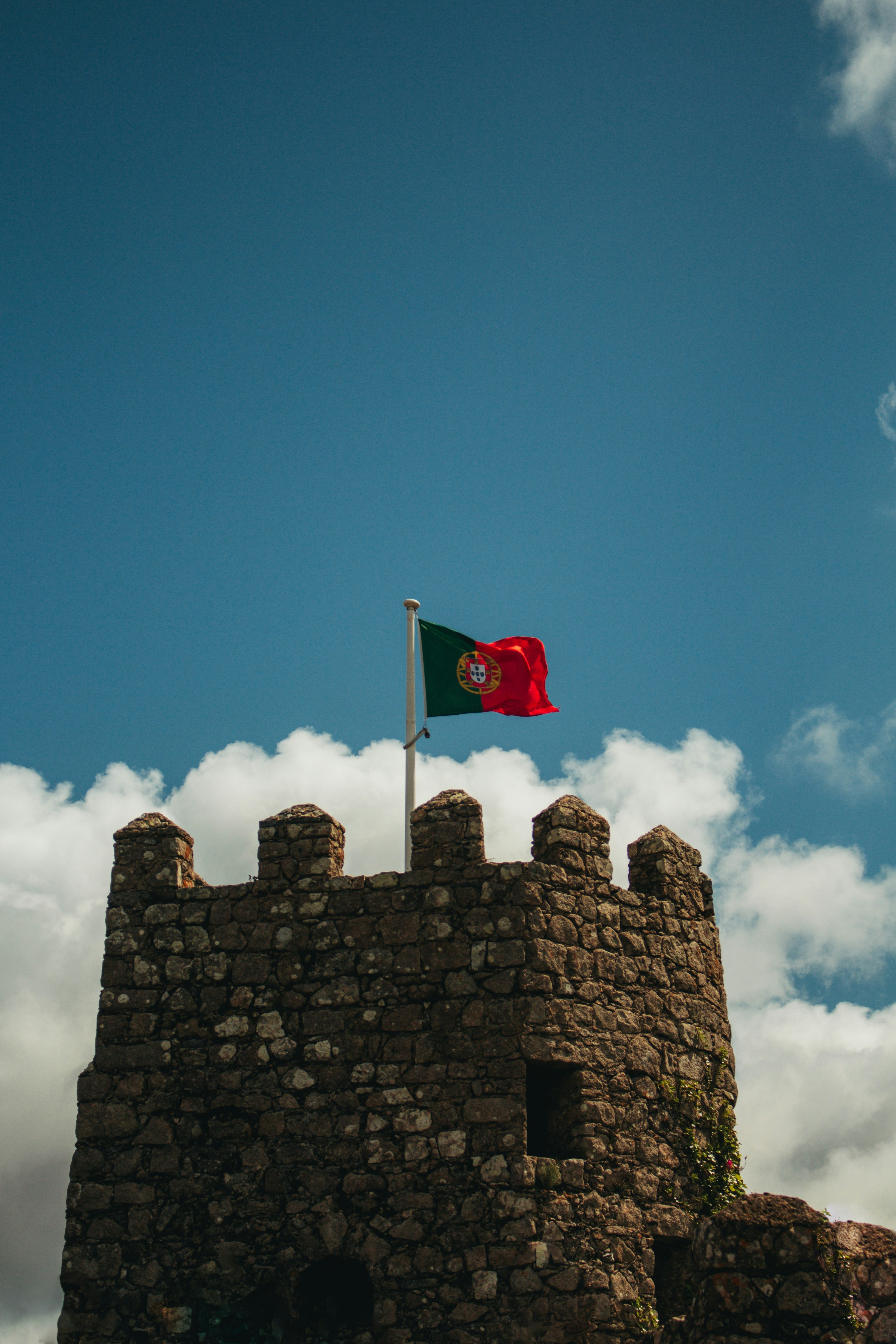The portuguese flag flies atop a stone castle.