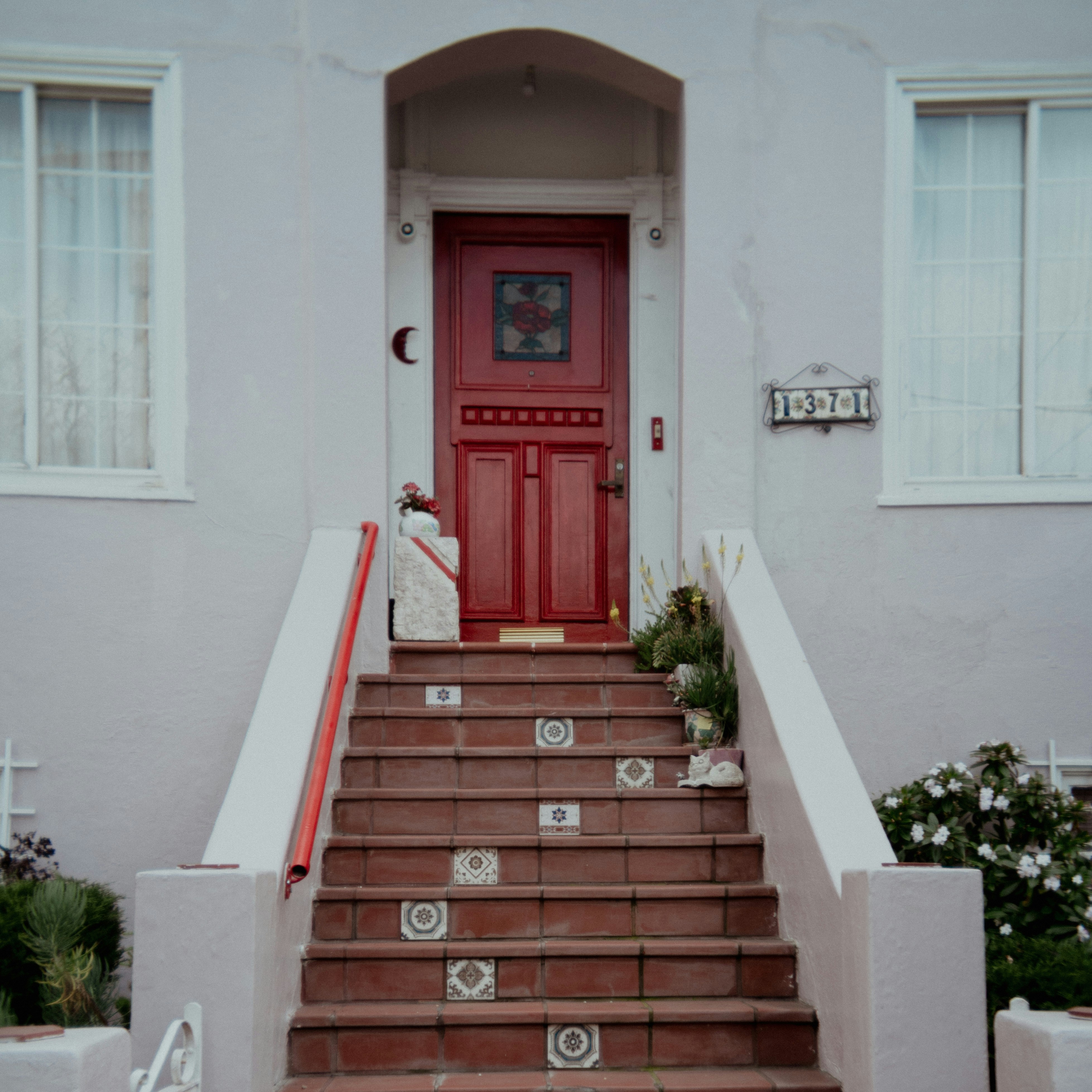 A red door leads to a charming house entrance.