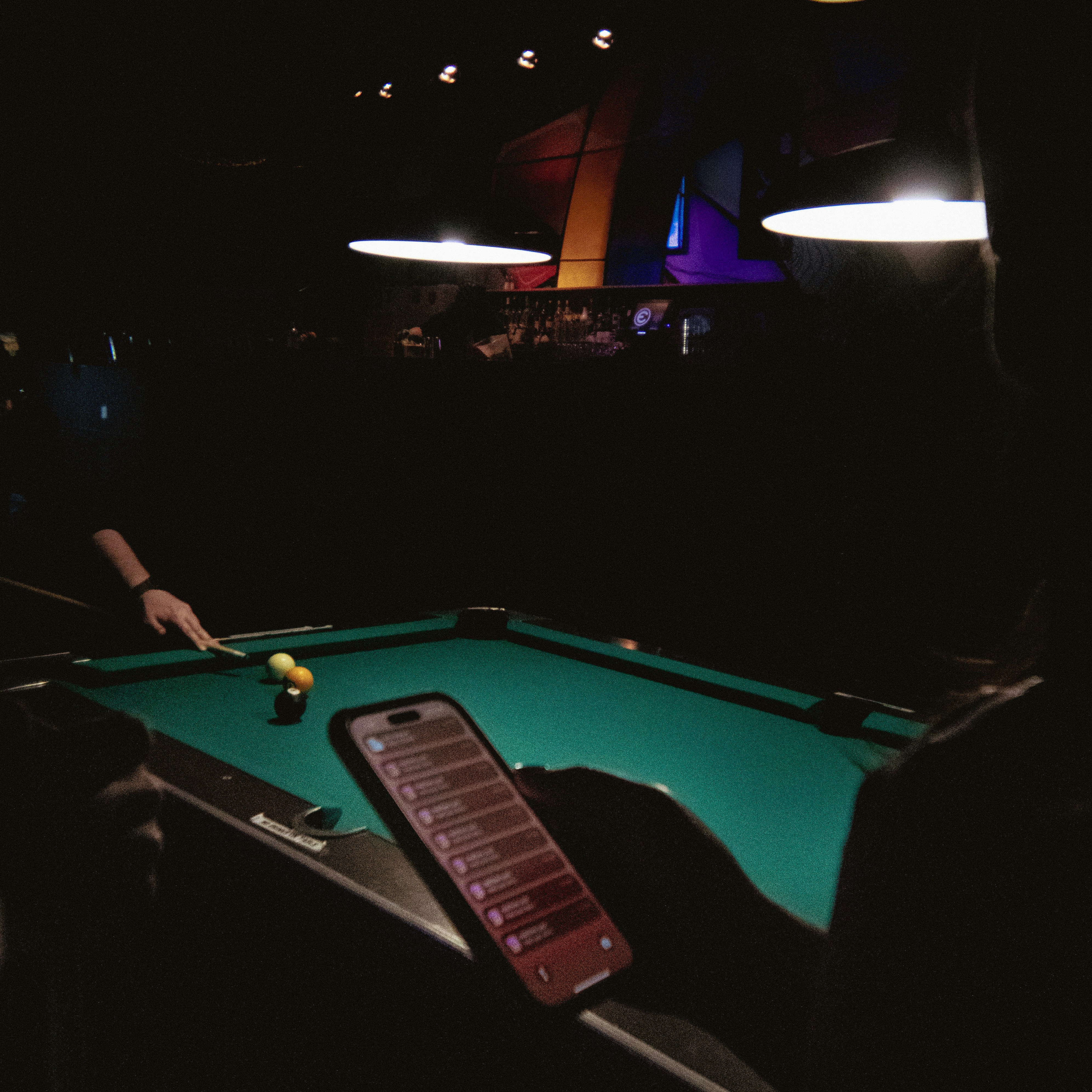 Playing pool with a phone and balls on table.