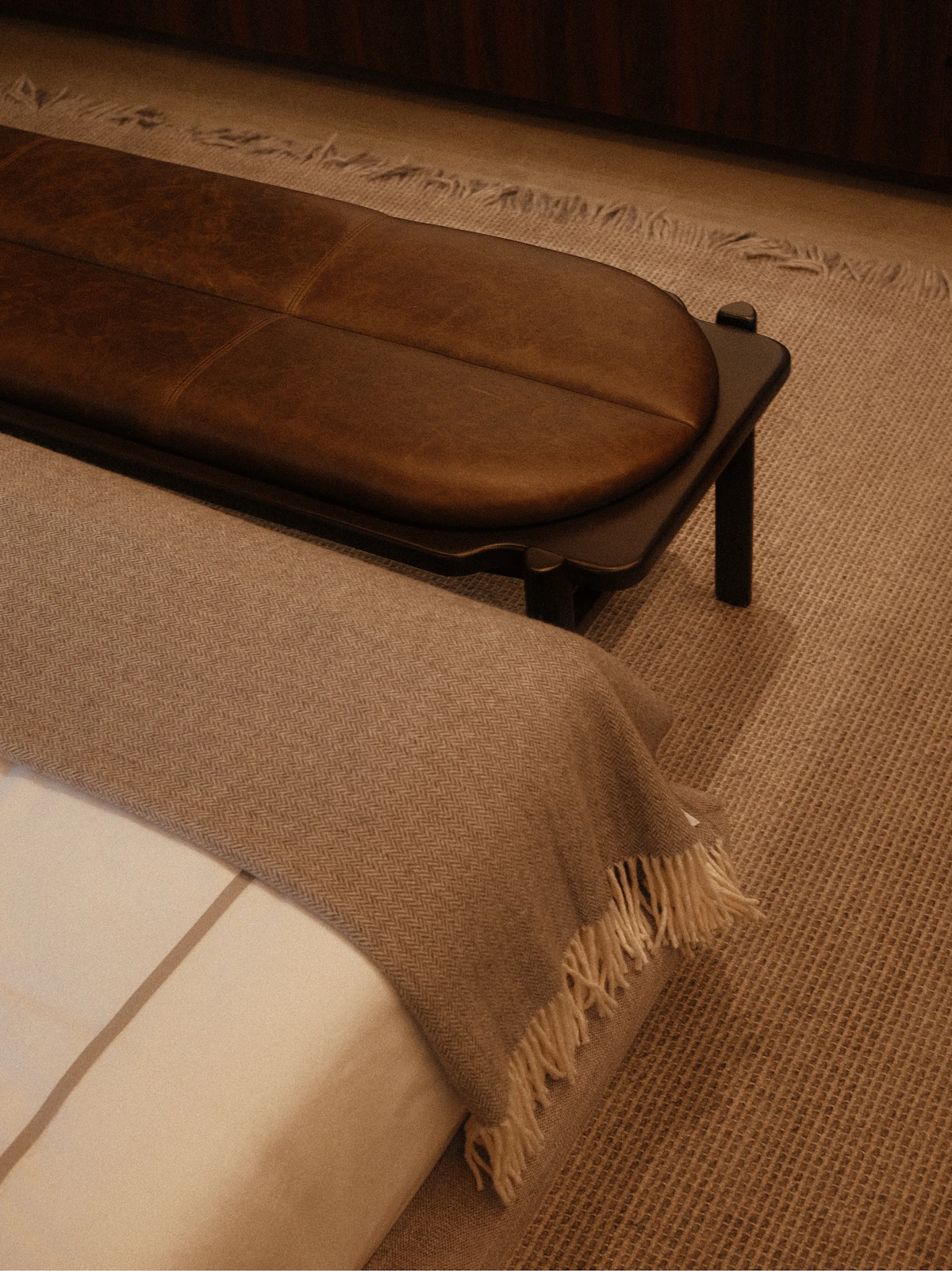 A made bed with a lambswool throw across the bed-end