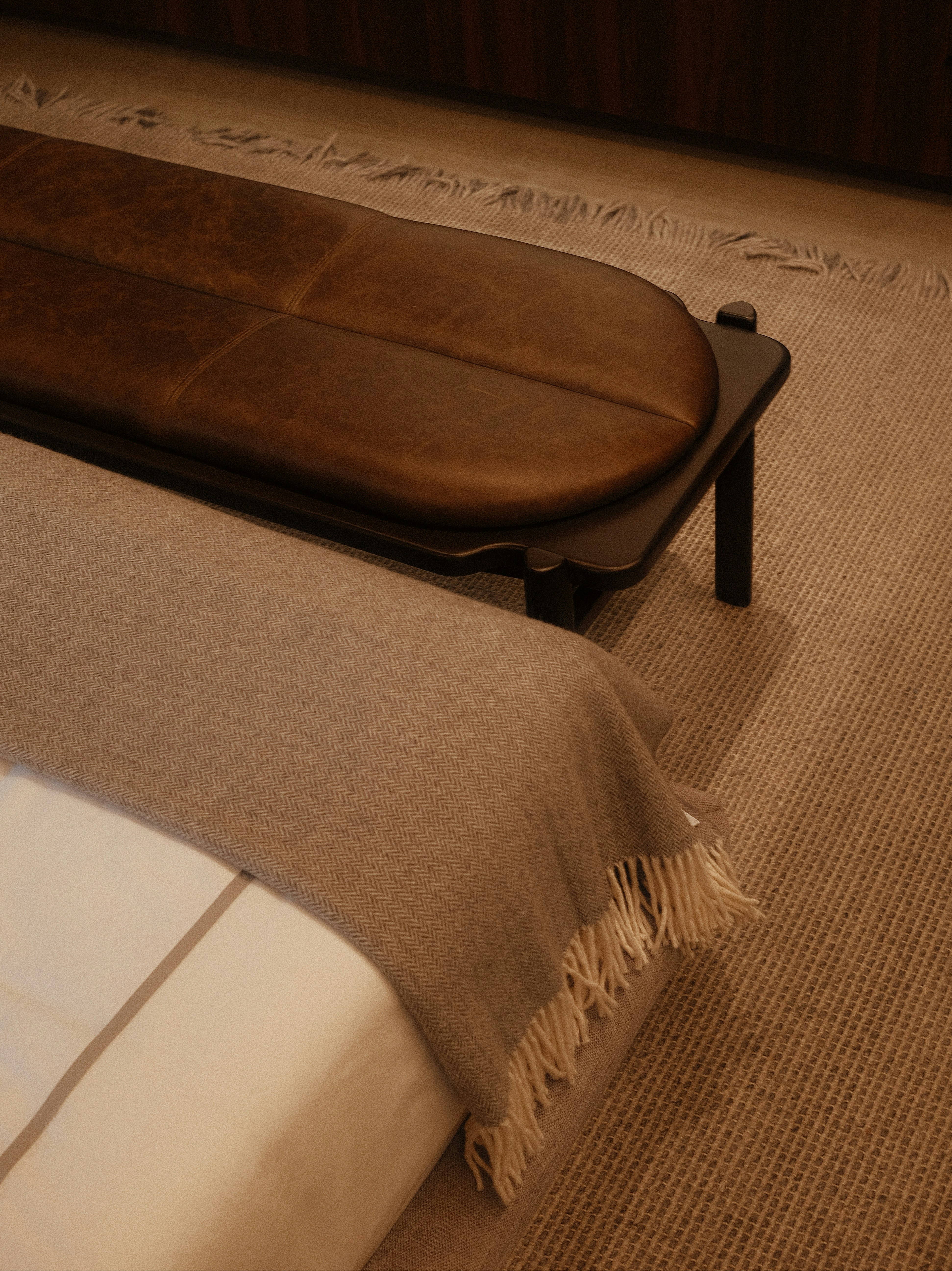 A bed with a bench and a soft blanket.