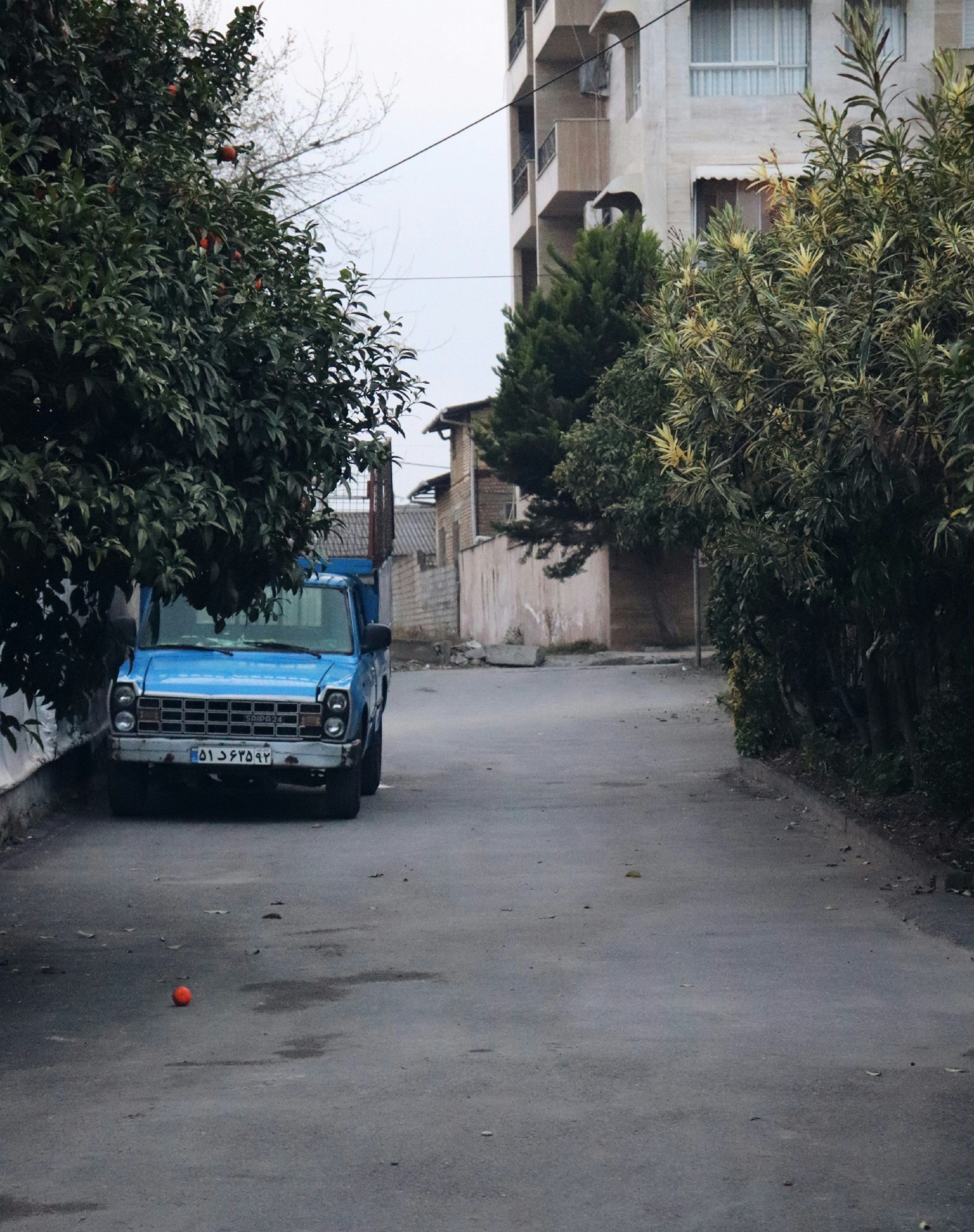 A blue truck sits on a quiet city street.