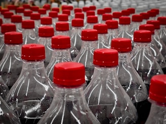 Bottles of soda are lined up with red lids.
