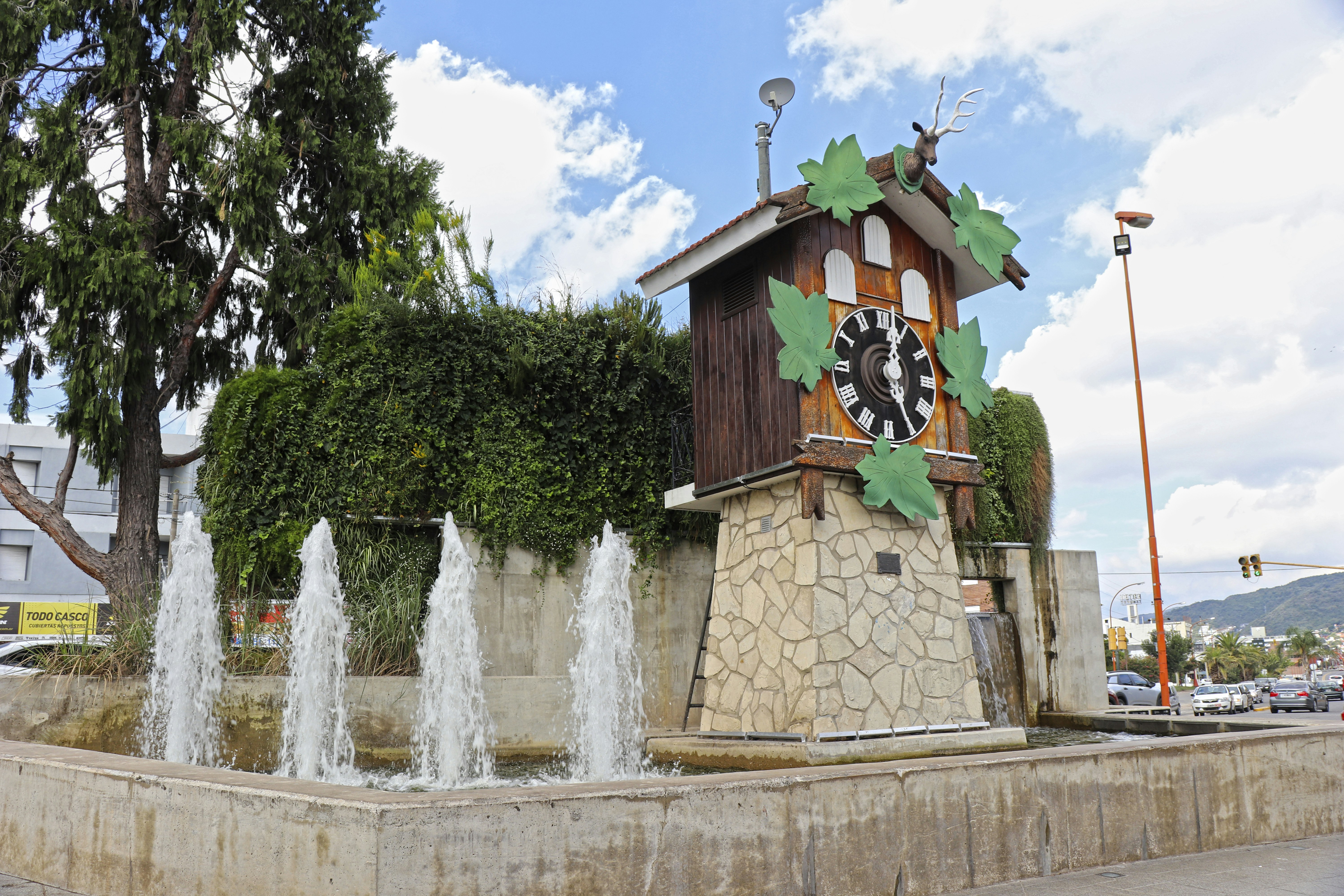 A cuckoo clock and fountain in a public square.